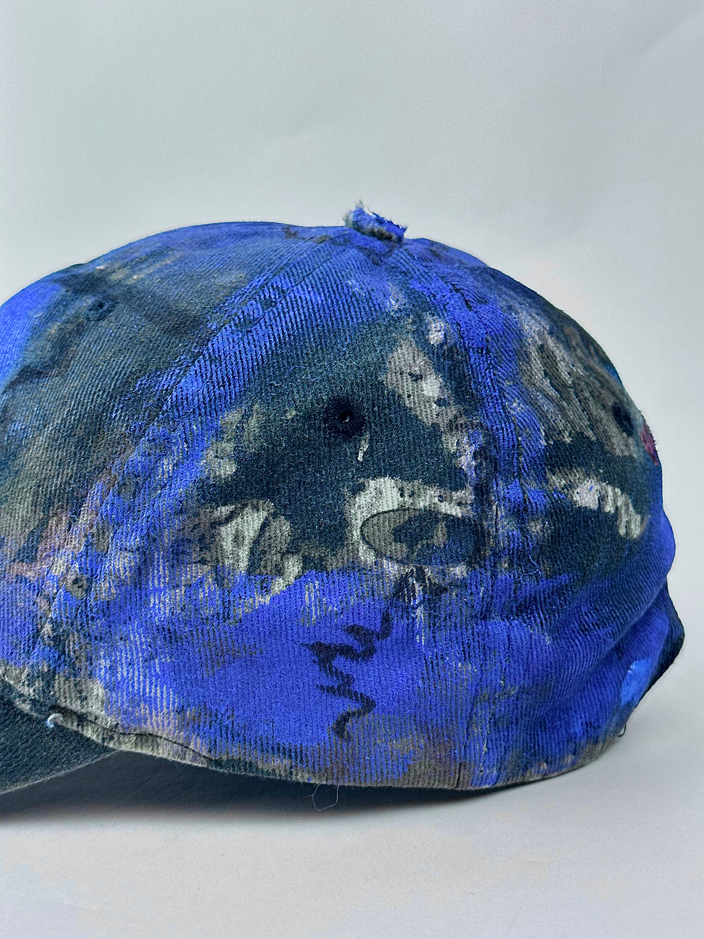 Left side back detail of ASTROBOI* x Mossy Oak 'Ultraviolet' showing hand drawn design detail and ultraviolet paint treatment on brown and purple camouflage hat.