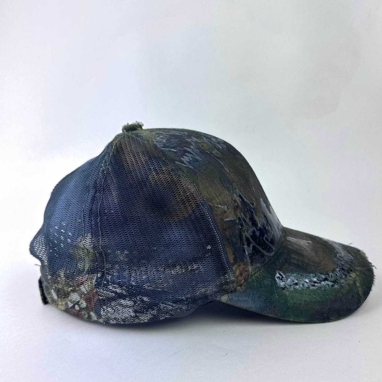 Right side detail of ASTROBOI* 'Mountains' showing Real Tree camouflage pattern and mesh back panel on trucker hat base.