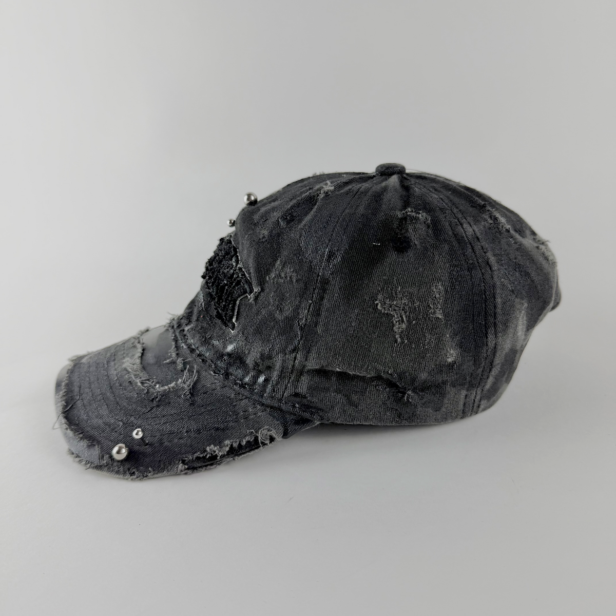 Left side detail of ASTROBOI* 'New York Grunge' showing black paint detail, distressing, and stainless steel piercing on black hat.