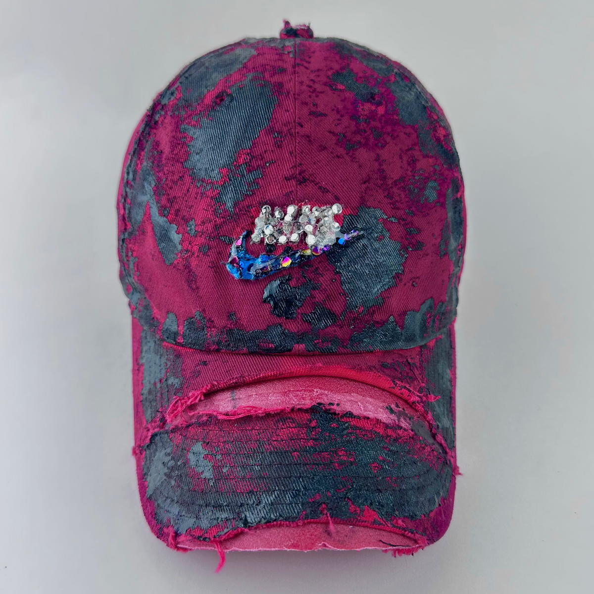 ASTROBOI* x Nike 'Comet' red and black painted distressed hat with Nike logo at center front, black painted pattern, and silver and multicolored rhinestones encased in clear resin, front view.