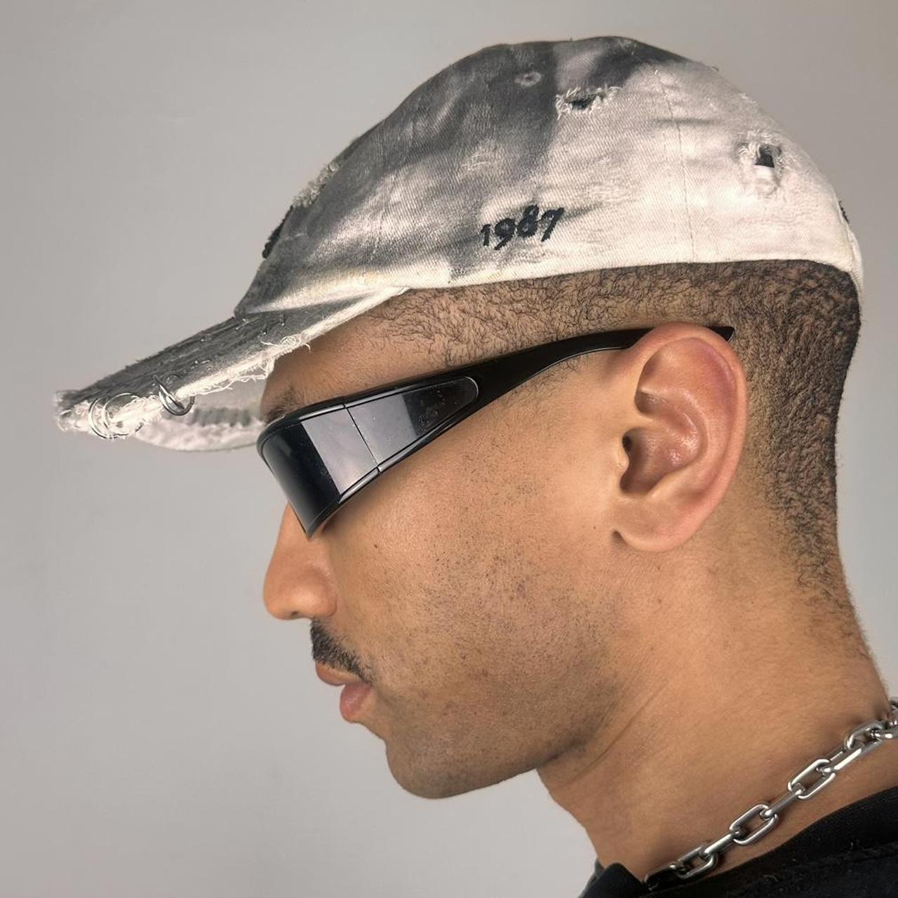 Left side of ASTROBOI* white NYC dad hat with clear resin logo, black and green abstract paint details, adjustable strap back