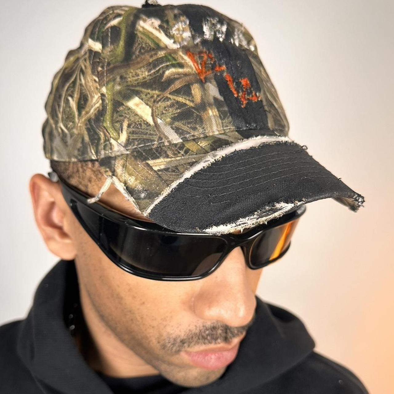 Front right of ASTROBOI* x Mossy Oak brown RealTree camouflage tattoo hat with SWA embroidery, black painted distressing, youth size, custom NYC piece
