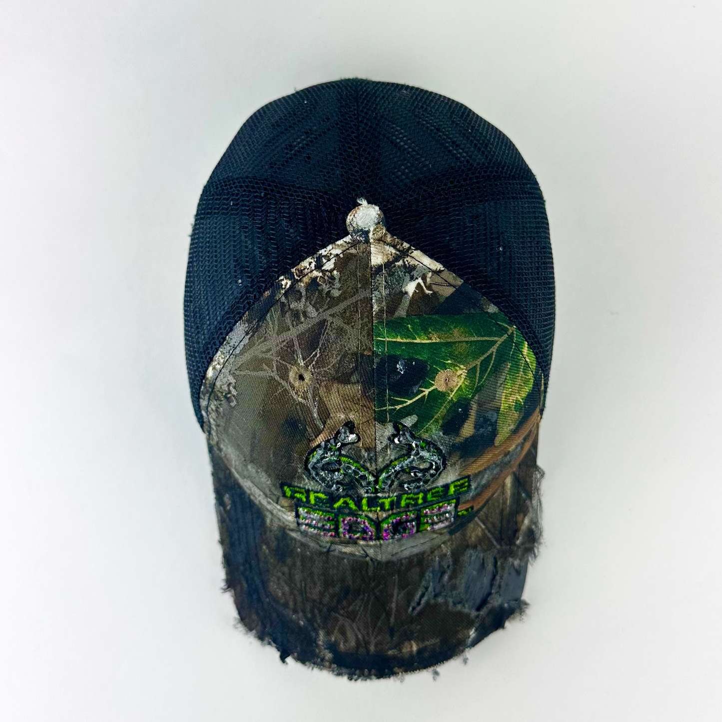 Top view of ASTROBOI* x RealTree 'Edge' showing black and purple/blue rhinestone embellishment on RealTree Edge branding and custom paint treatment on brown camo fabric.