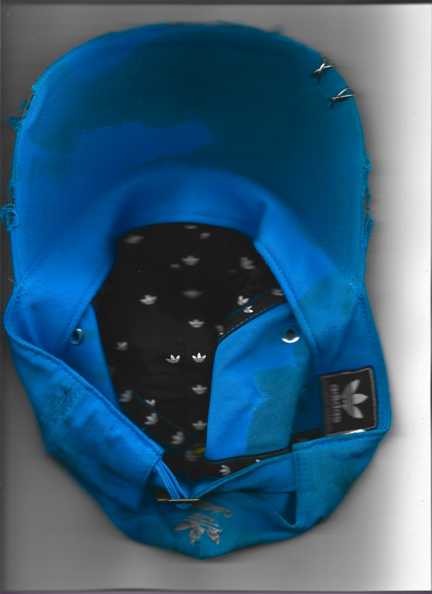 Scanned image of ASTROBOI* x Adidas 'Nebula' blue distressed pierced hat, rear view showing white Adidas back logo and adjustable strap.
