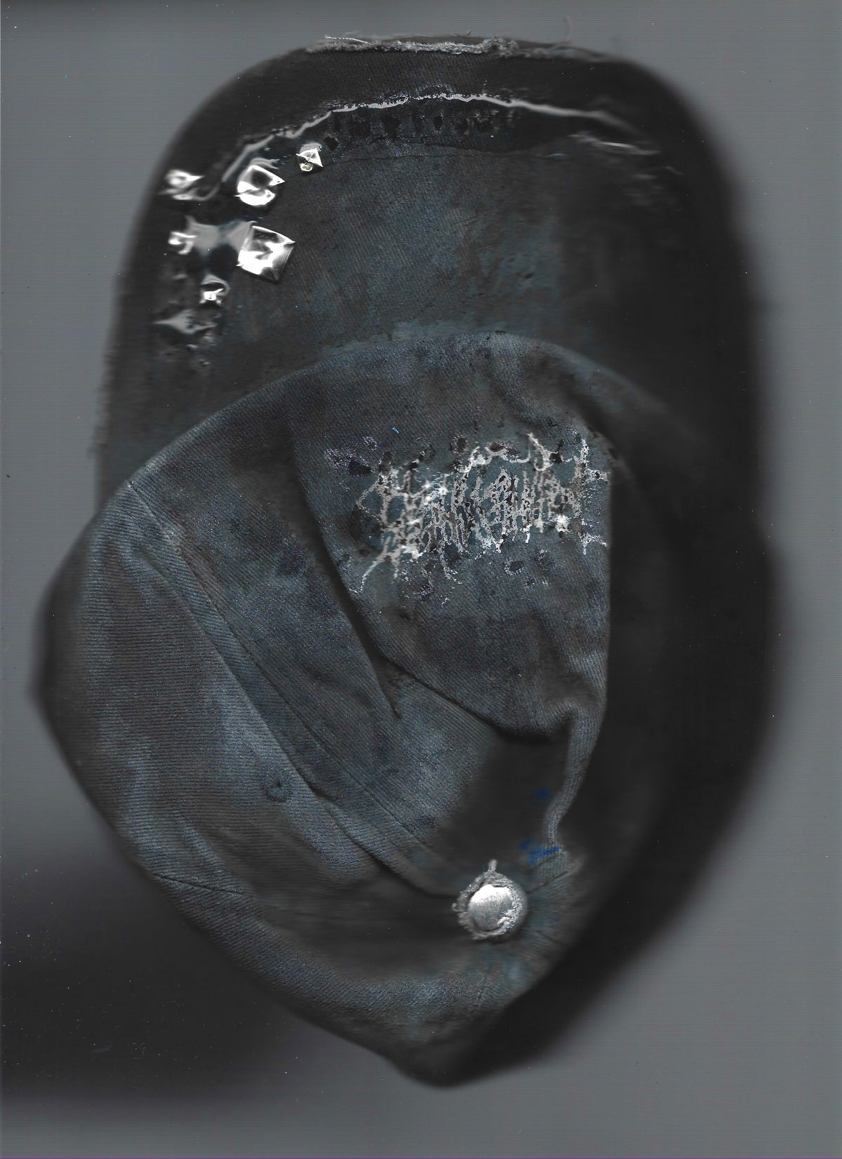 Scanned image of ASTROBOI* 'Slick' showing silver studded visor detail and 3D resin coating on black and gray base, front view. 