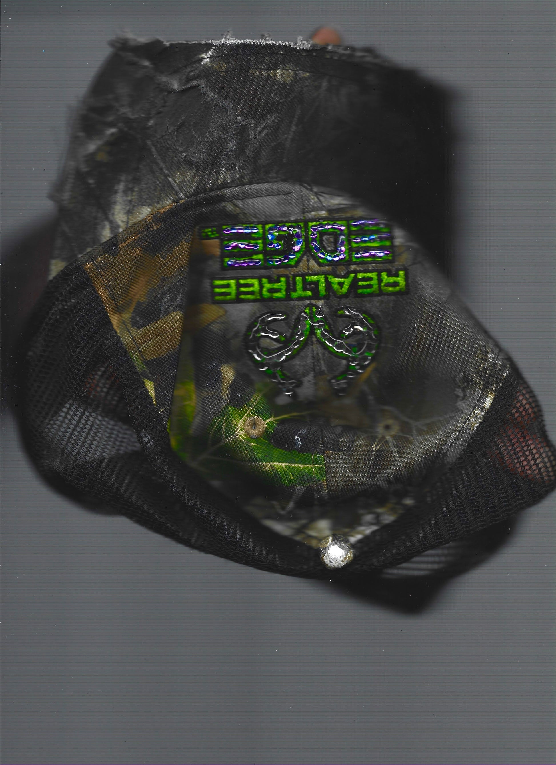 Scanned front view of ASTROBOI* x RealTree 'Edge' brown camo rhinestone cap with black and purple/blue rhinestone-embellished RealTree Edge branding across the top and partially sawed-off brim.