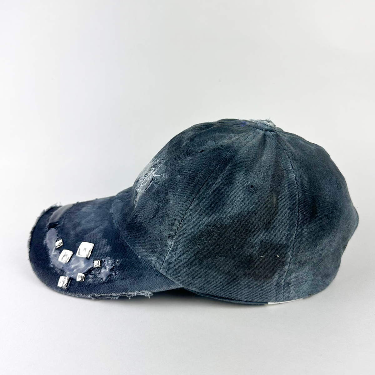 Left side detail of ASTROBOI* 'Slick' showing custom paint treatment and silver stud and resin visor detail on black and gray indie cap.
