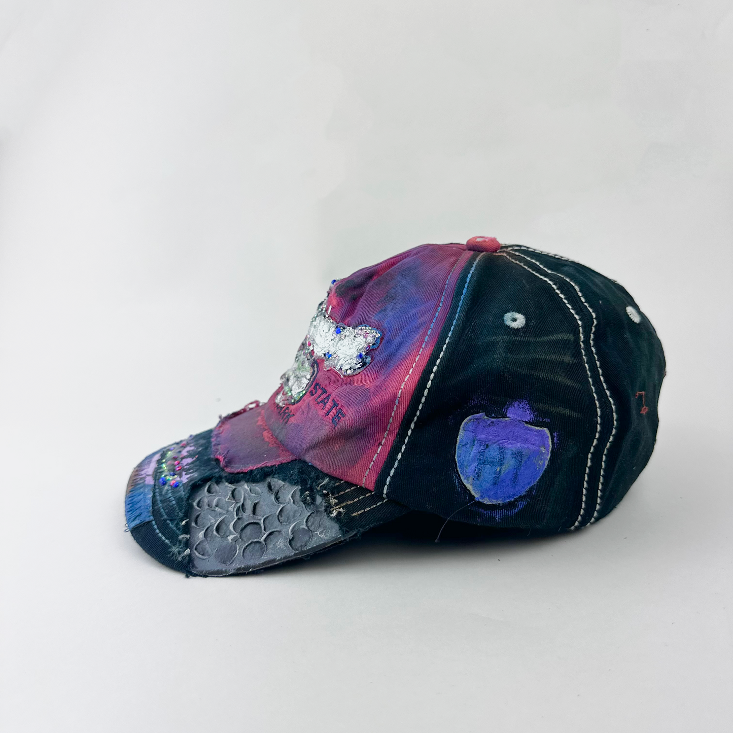 Left side detail of ASTROBOI* 'Tropicale' showing deconstructed visor and metallic paint and rhinestone detail on Hawaii Y2K hat.