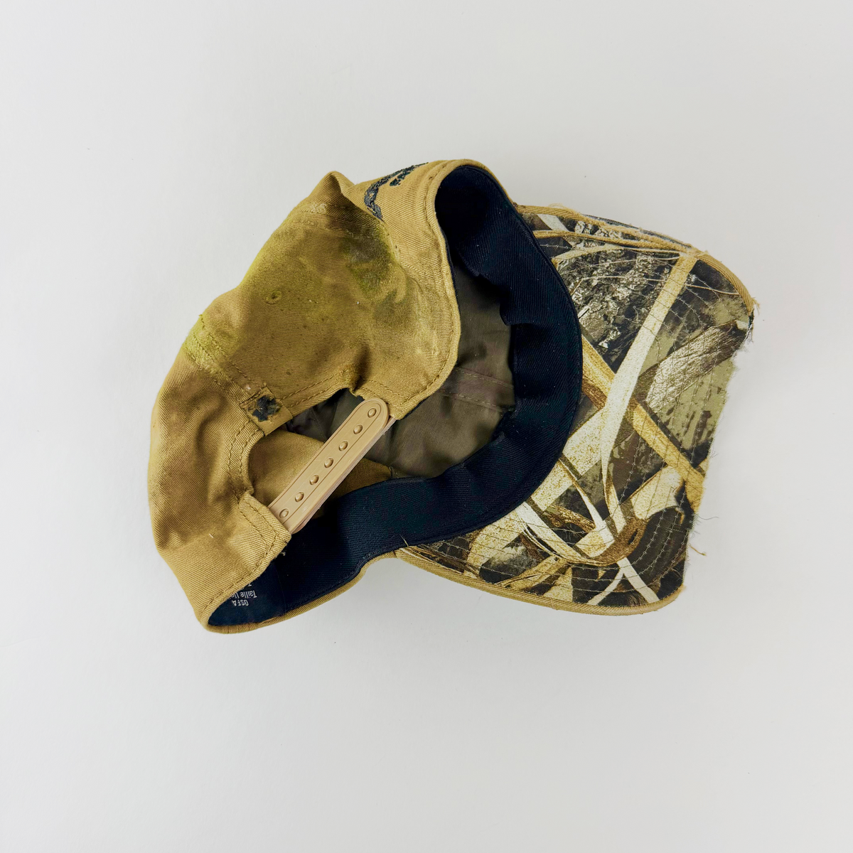 Rear view of ASTROBOI* x Under Armour 'Dolor' tan distressed cap showing adjustable strap closure.