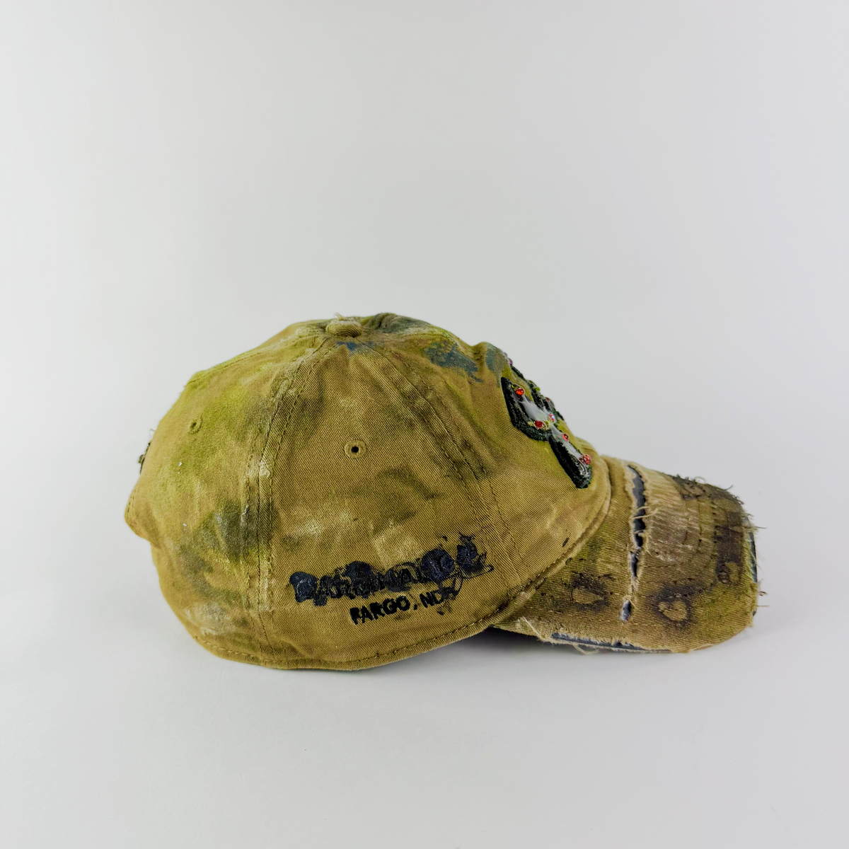 Side detail showing distressed tan fabric, custom paint treatment, and partially sawed-off brim.