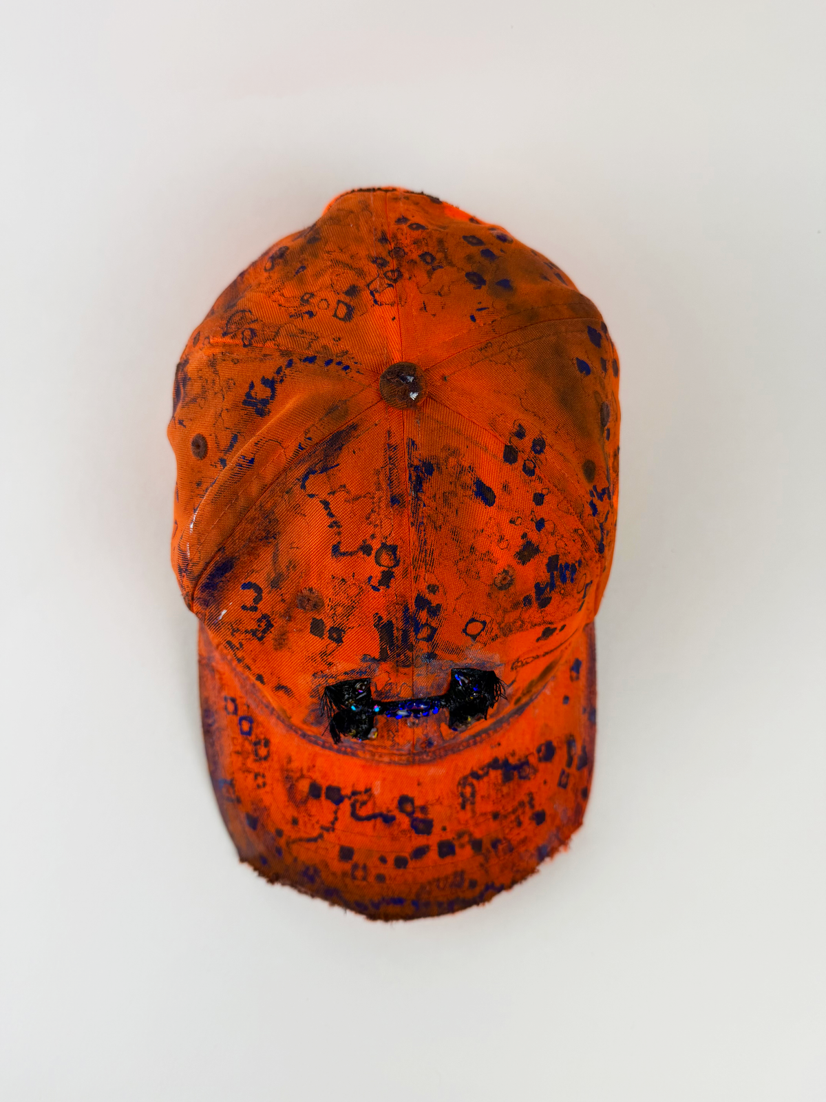 ASTROBOI* x Under Armour ‘Solar Flare’ orange and blue futuristic rhinestone cap with hand drawn blue abstract design, rhinestone-embellished frayed logo, and partially sawed-off visor, top view.