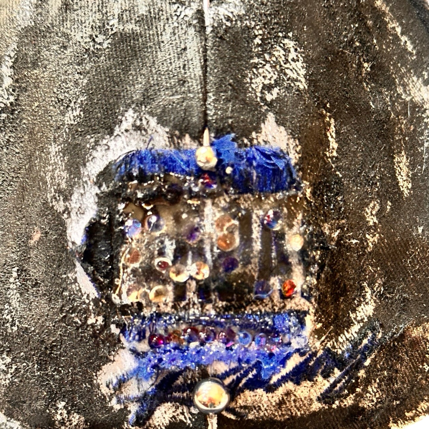 Logo detail of Blue and white ASTROBOI* NAPA hat with rhinestone-covered logo sealed in clear resin, stainless steel piercings, and a deconstructed visor, handcrafted in NYC.