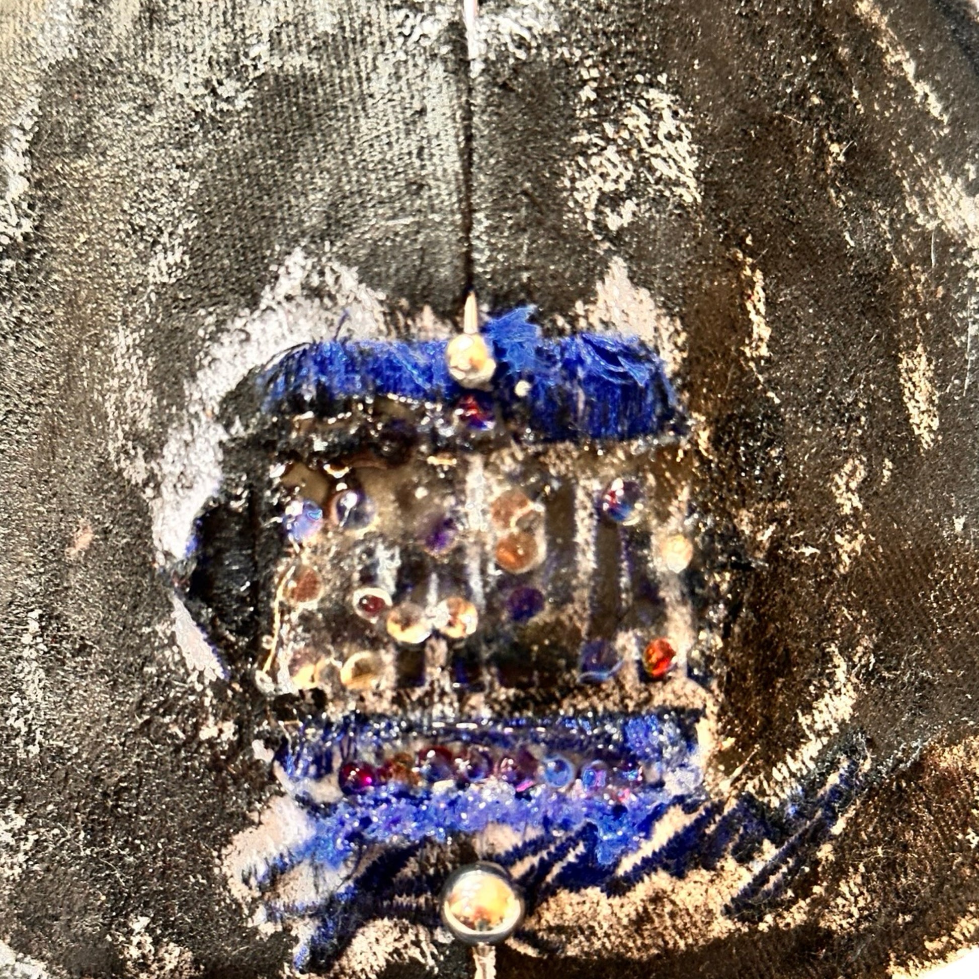 Logo detail of Blue and white ASTROBOI* NAPA hat with rhinestone-covered logo sealed in clear resin, stainless steel piercings, and a deconstructed visor, handcrafted in NYC.