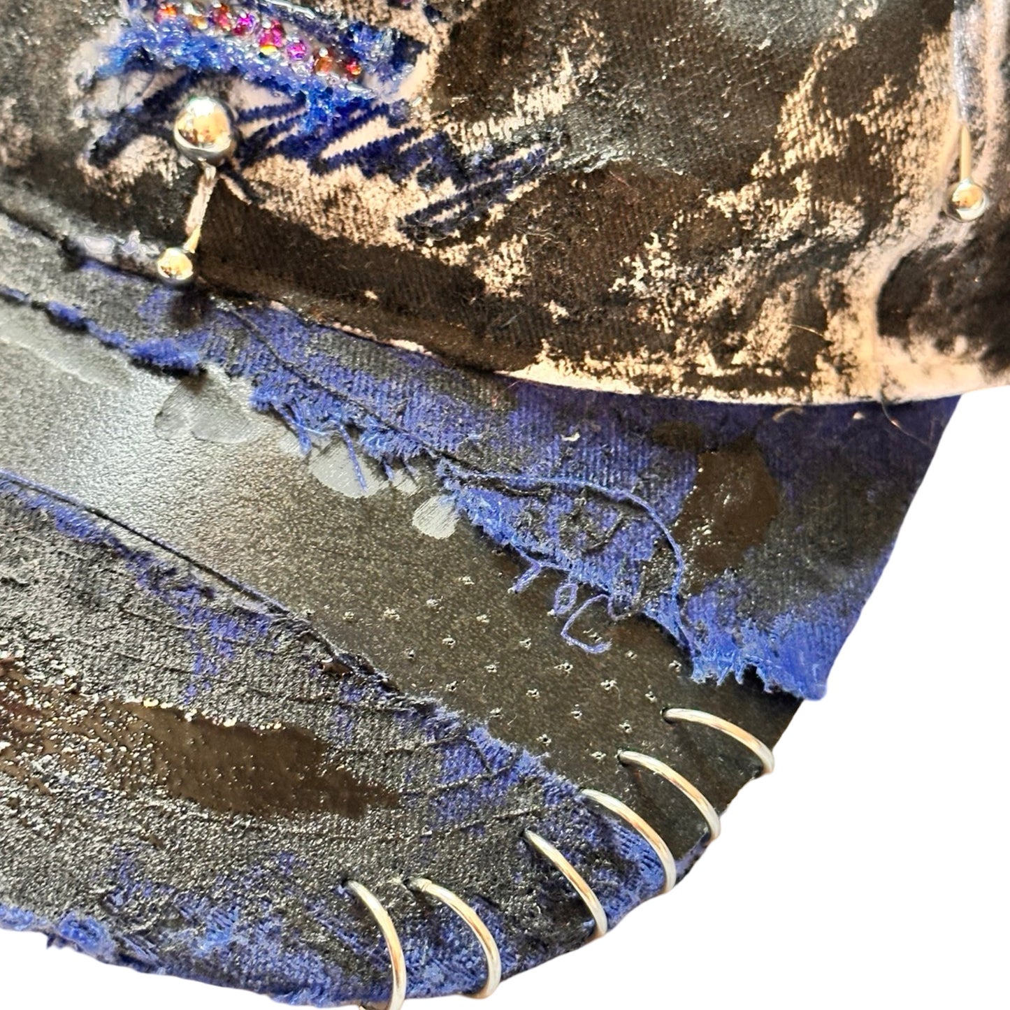 Flat front visor detail of Blue and white ASTROBOI* NAPA hat with rhinestone-covered logo sealed in clear resin, stainless steel piercings, and a deconstructed visor, handcrafted in NYC.