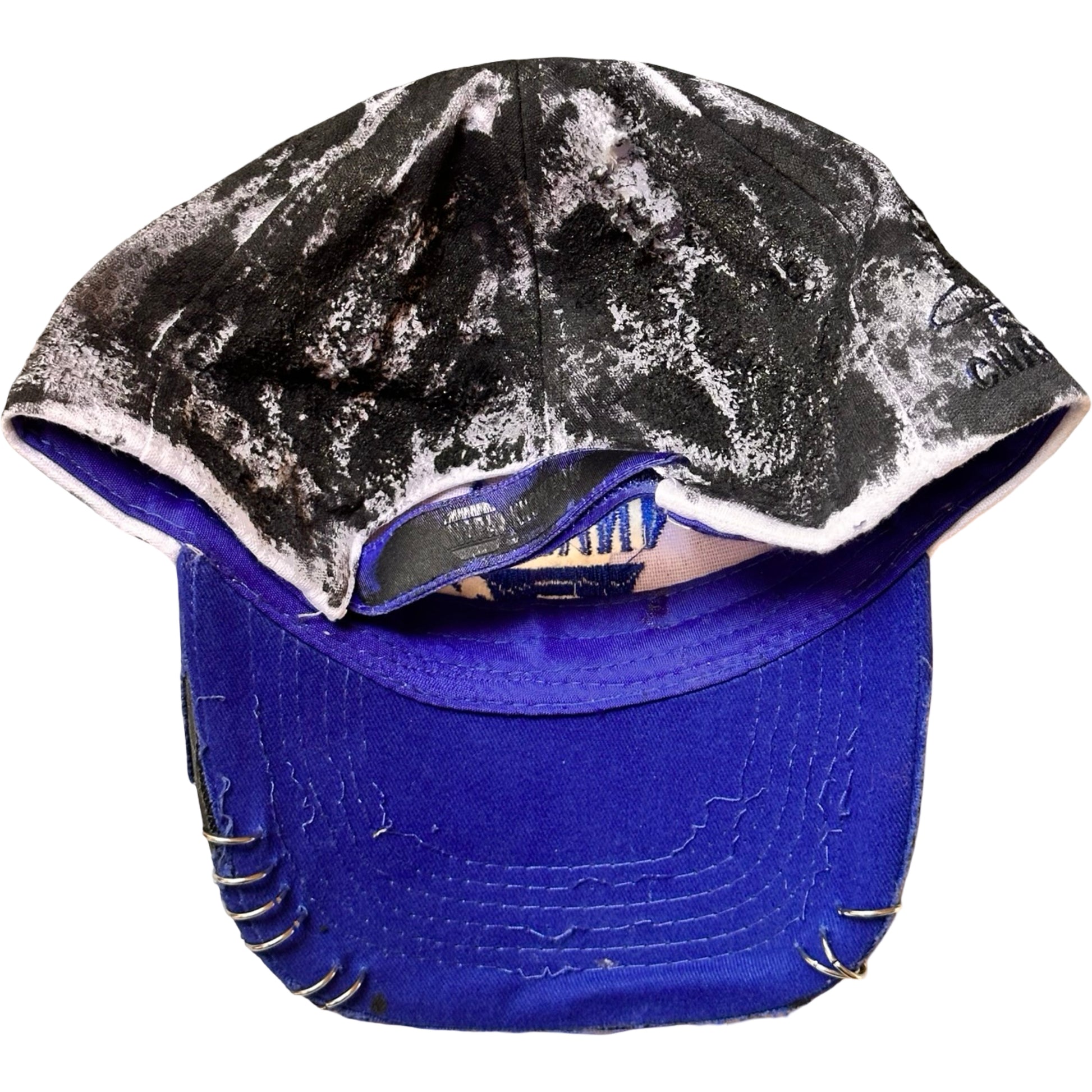 Flat back of Blue and white ASTROBOI* NAPA hat with rhinestone-covered logo sealed in clear resin, stainless steel piercings, and a deconstructed visor, handcrafted in NYC.