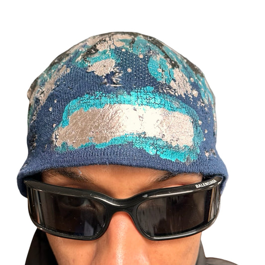 Front close up of ASTROBOI* black and blue distressed flame beanie with metallic paint and tonal rhinestones. Custom acrylic knit hat handmade in NYC.