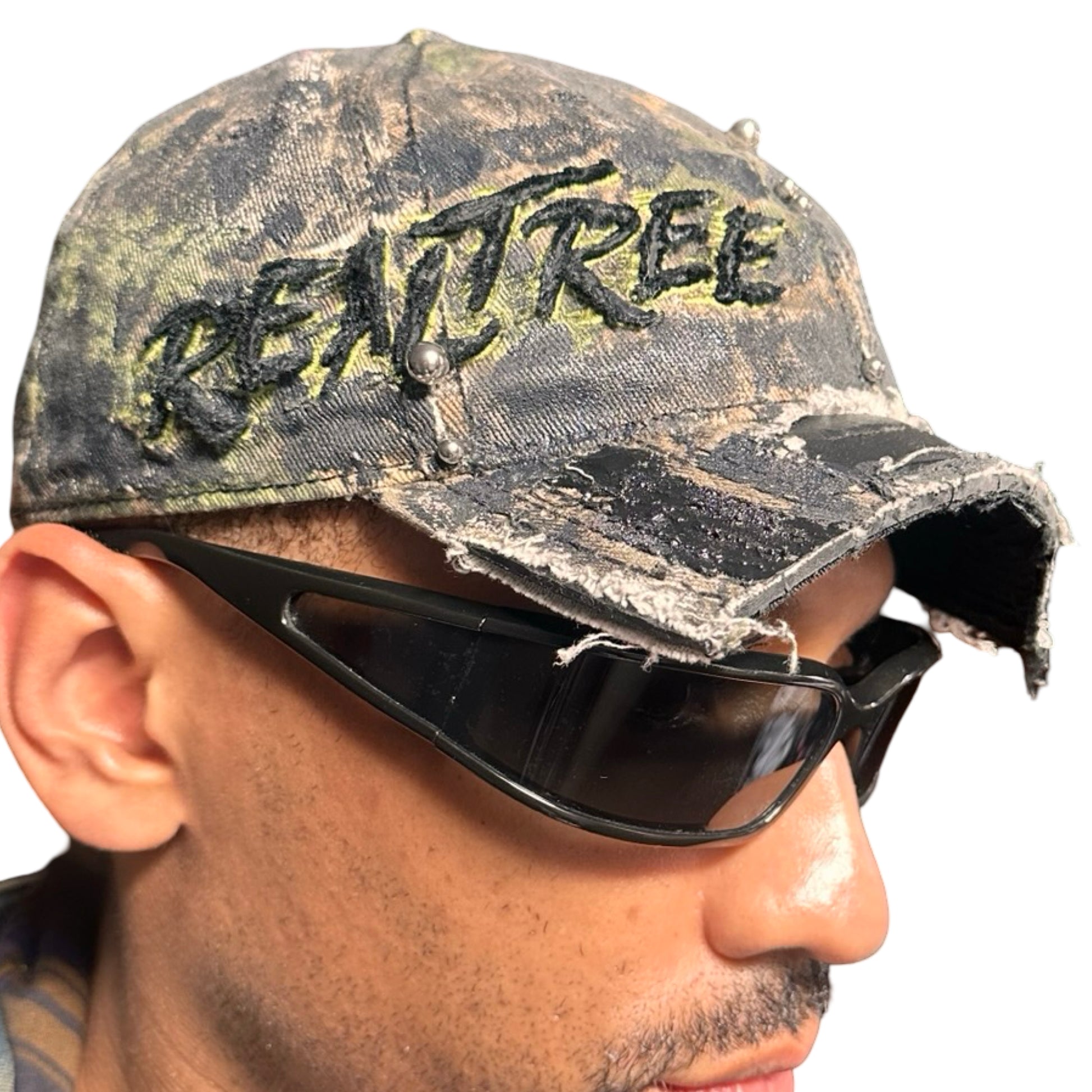 Front right of Brown RealTree distressed half-visor hat with elastic base, black resin detailing, and a sawed-off visor for a deconstructed Y2K aesthetic.