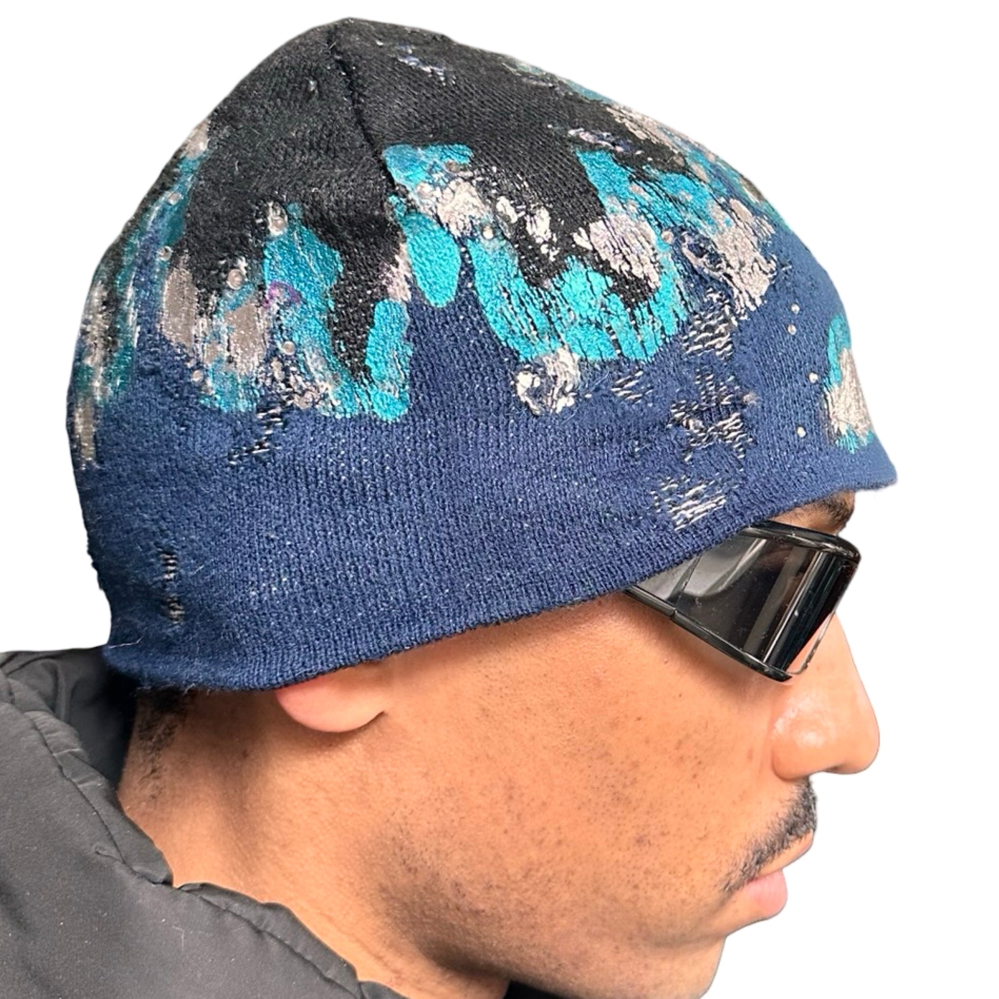 Right of ASTROBOI* black and blue distressed flame beanie with metallic paint and tonal rhinestones. Custom acrylic knit hat handmade in NYC.