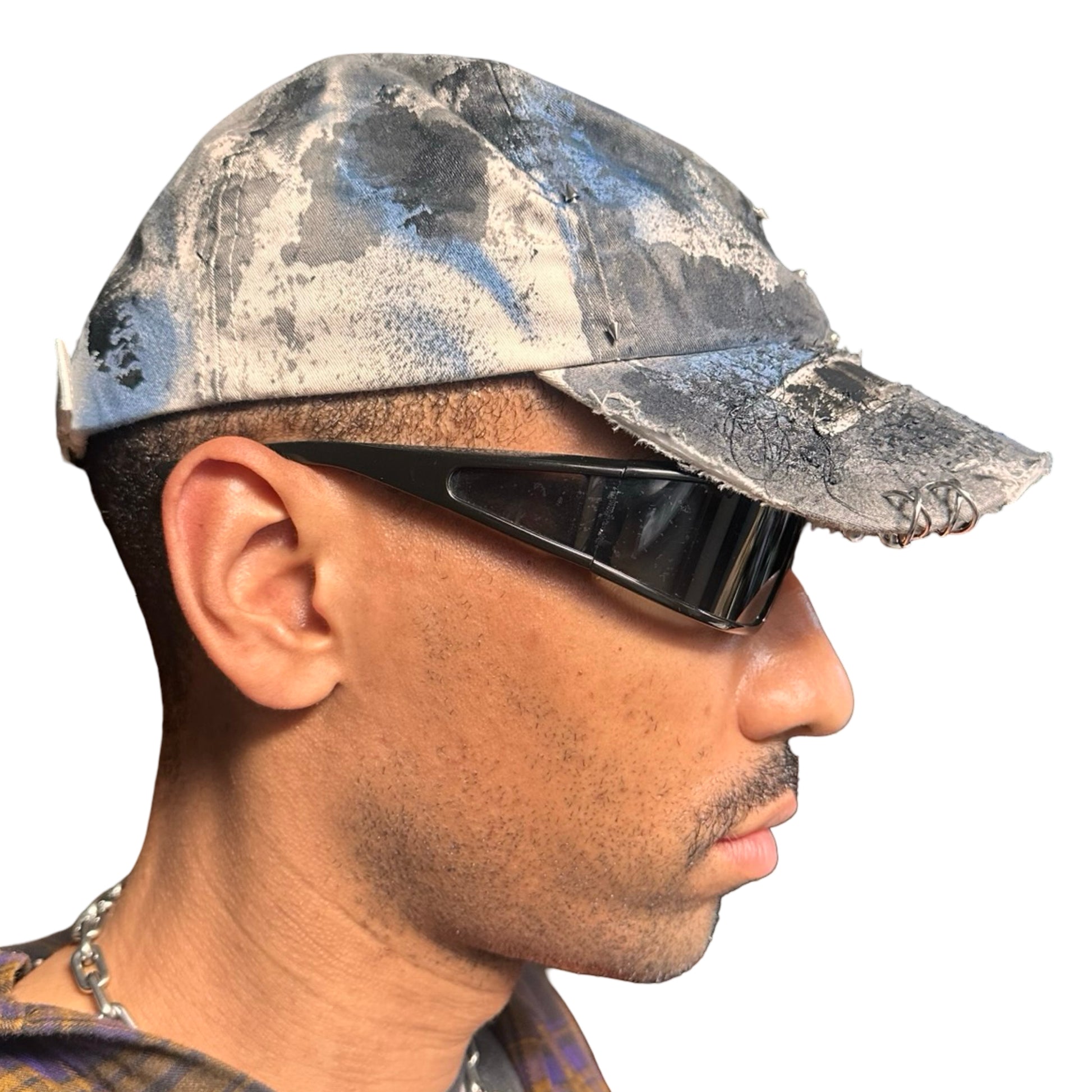 Right of Black Vuori baseball hat customized by ASTROBOI* with blue and black painted details, stainless steel piercings, and an embroidered V logo.