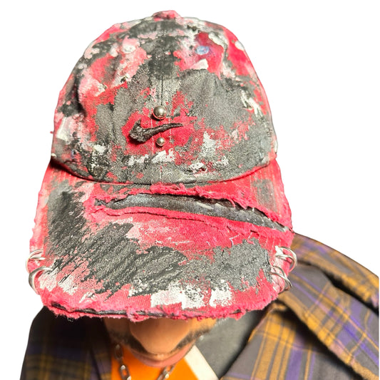 Front of Burgundy Nike hat with black/white paint, distressing, and stainless steel piercings, customized by ASTROBOI*.