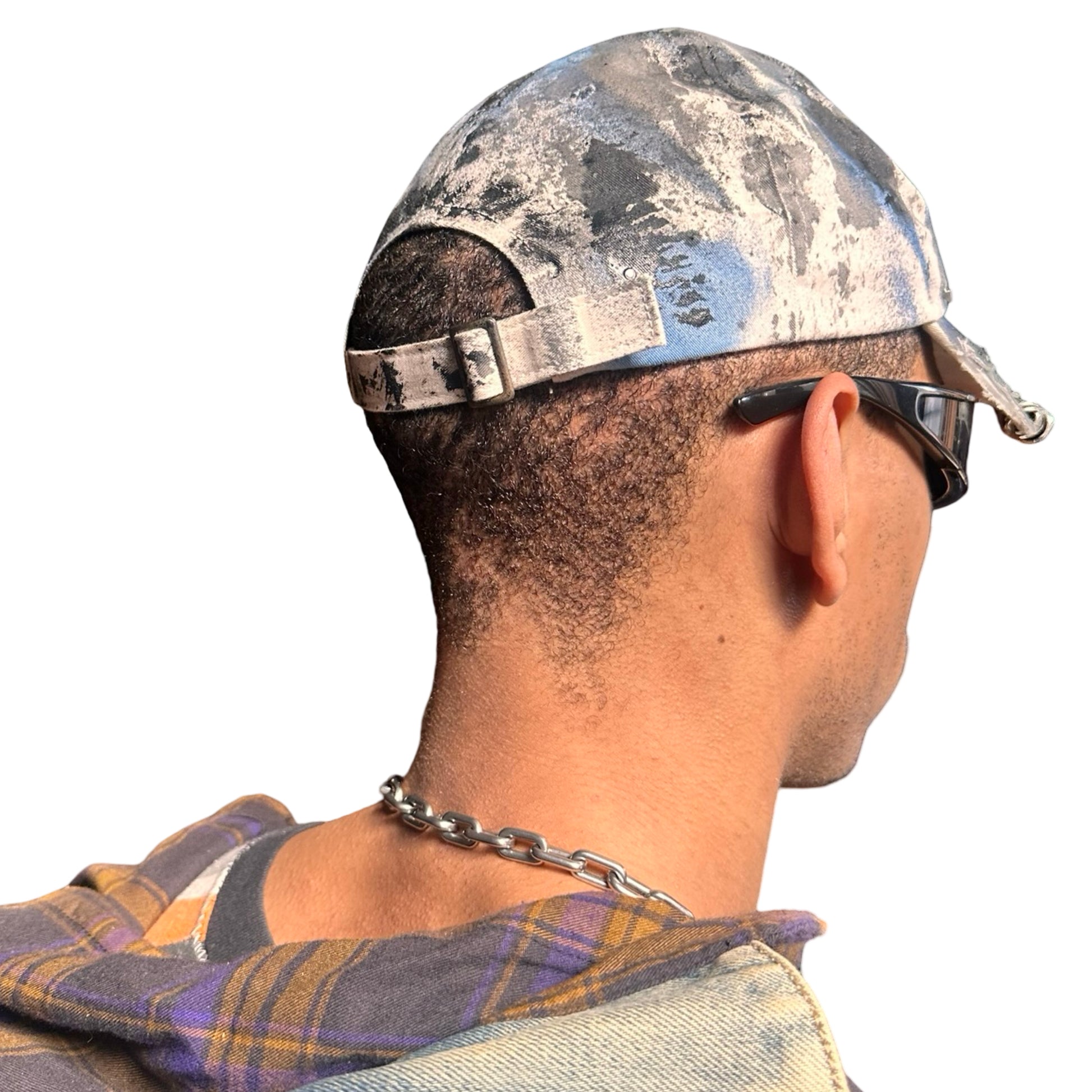 Back of Black Vuori baseball hat customized by ASTROBOI* with blue and black painted details, stainless steel piercings, and an embroidered V logo.