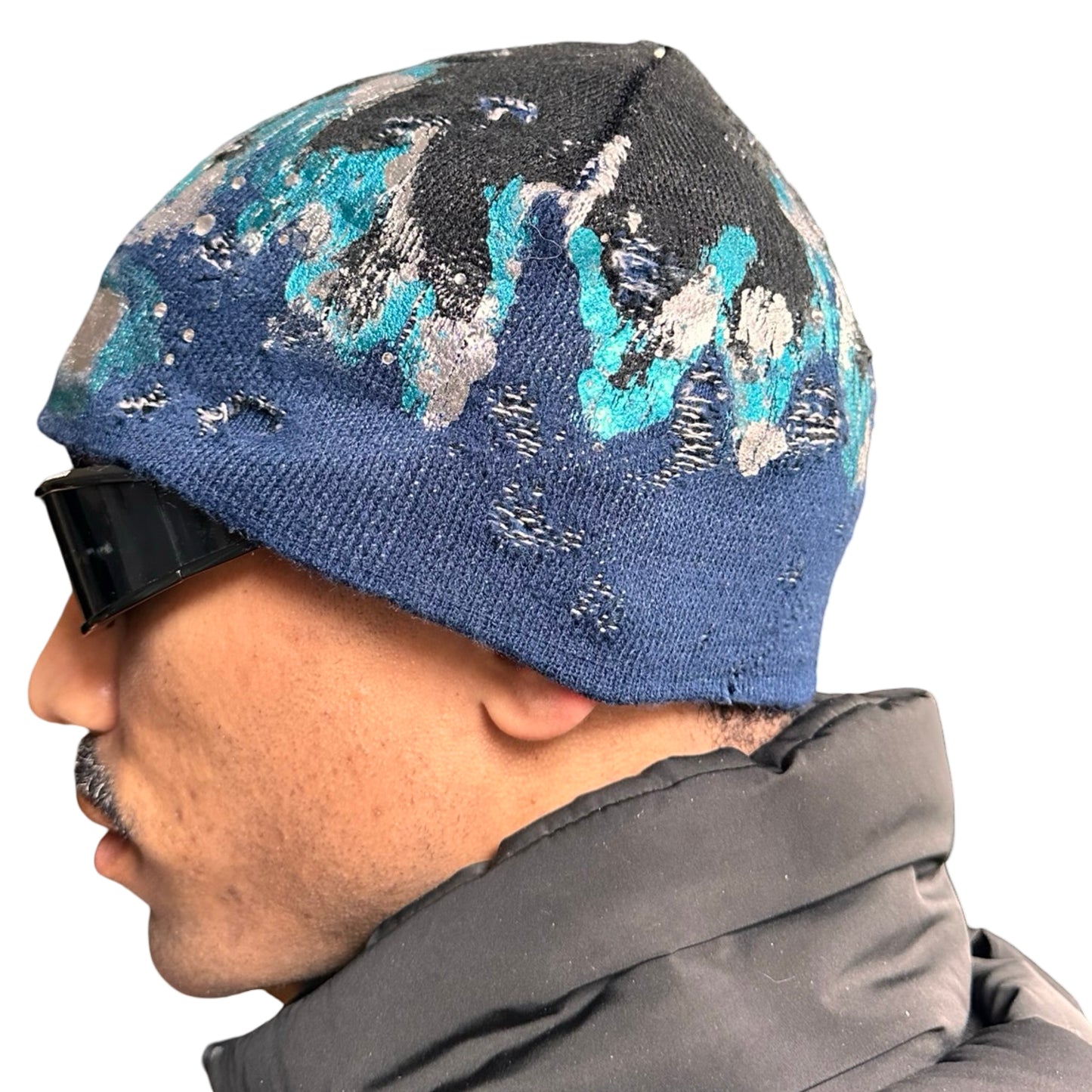 Left of ASTROBOI* black and blue distressed flame beanie with metallic paint and tonal rhinestones. Custom acrylic knit hat handmade in NYC.