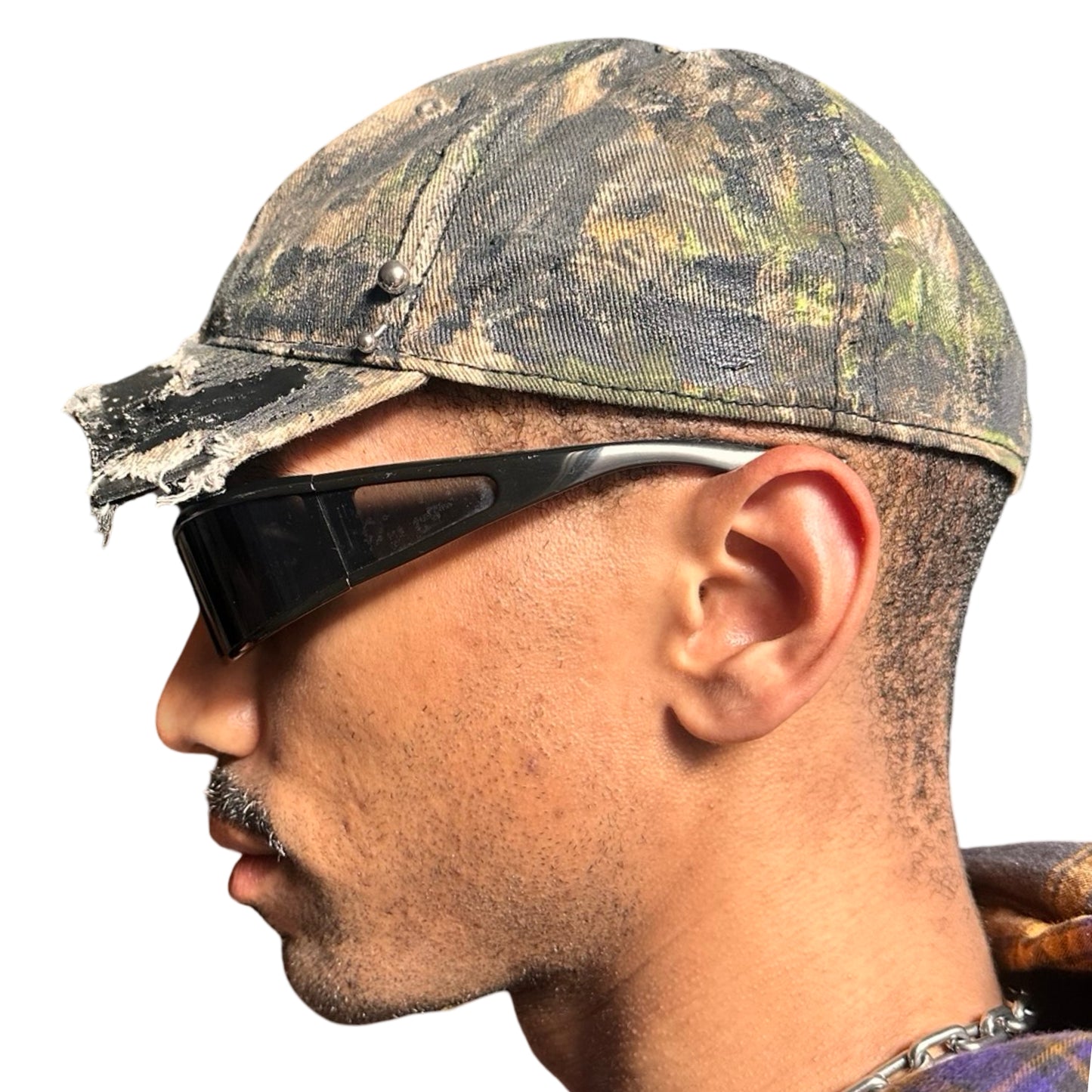 Left side of Brown RealTree distressed half-visor hat with elastic base, black resin detailing, and a sawed-off visor for a deconstructed Y2K aesthetic.