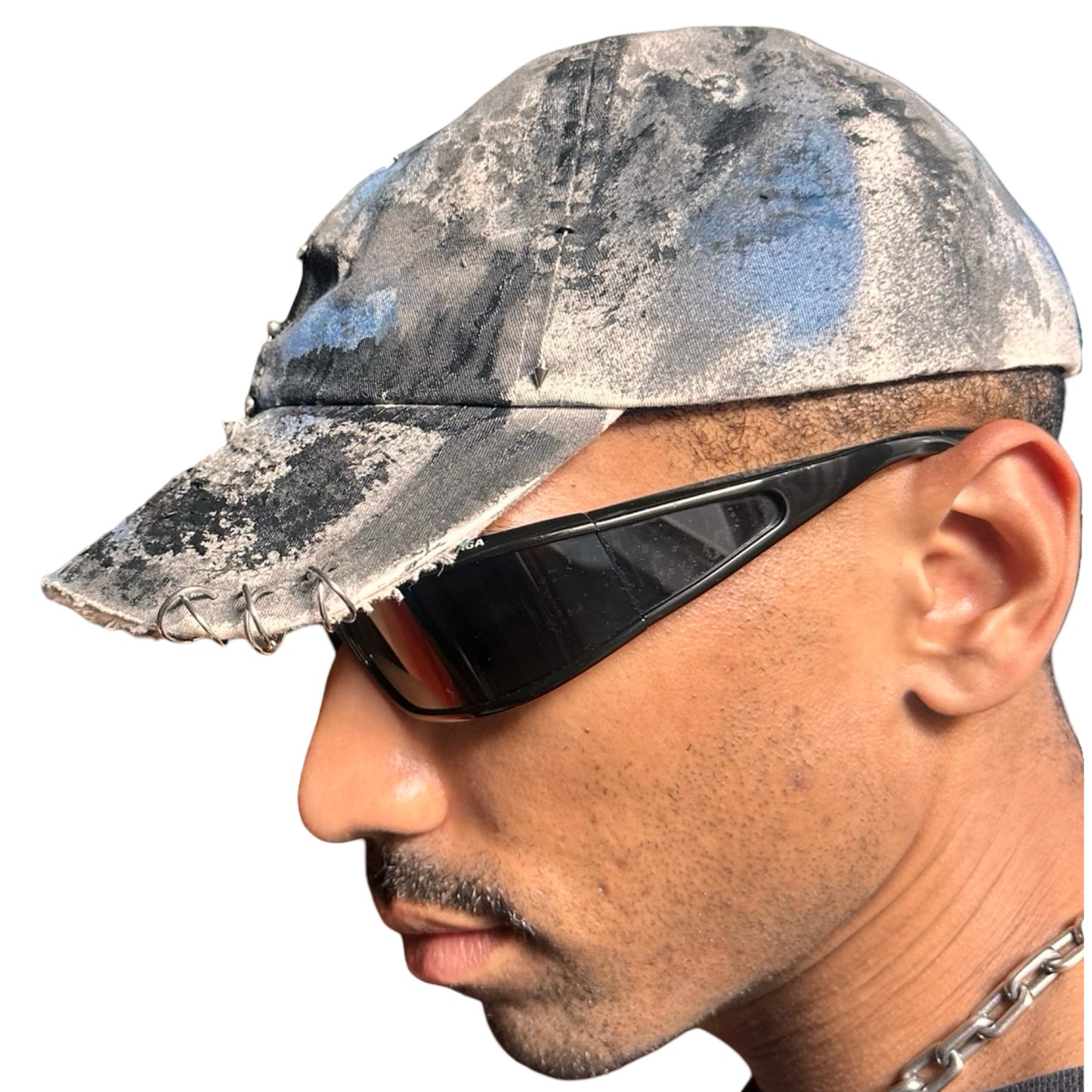 Left of Black Vuori baseball hat customized by ASTROBOI* with blue and black painted details, stainless steel piercings, and an embroidered V logo.