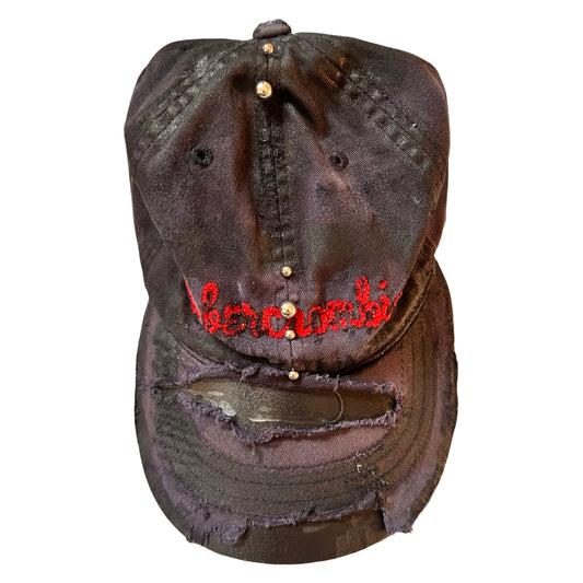 Flat front of Navy ASTROBOI* x Abercrombie hat with distressed paint, stainless steel piercings, and logo embroidery on front and back, customized in NYC.