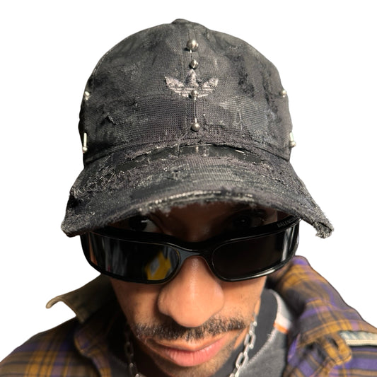 Front of Black Adidas hat customized by ASTROBOI* with distressing, black painted accents, and stainless steel piercings.