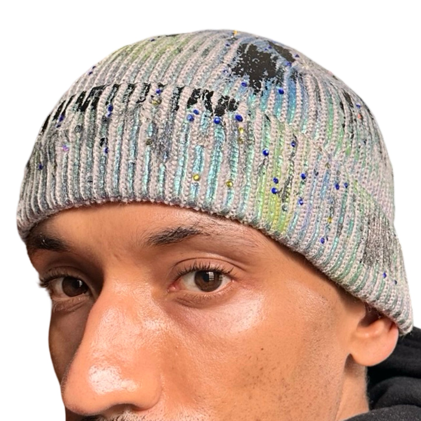 Front of ASTROBOI* blue-green iridescent beanie featuring black metallic paint accents and tonal rhinestones, custom-made in NYC for a bold streetwear look.