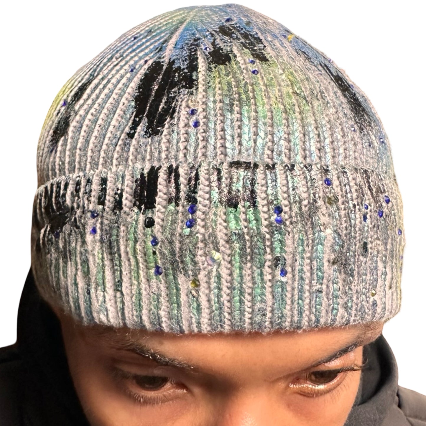 Front close up of ASTROBOI* blue-green iridescent beanie featuring black metallic paint accents and tonal rhinestones, custom-made in NYC for a bold streetwear look.