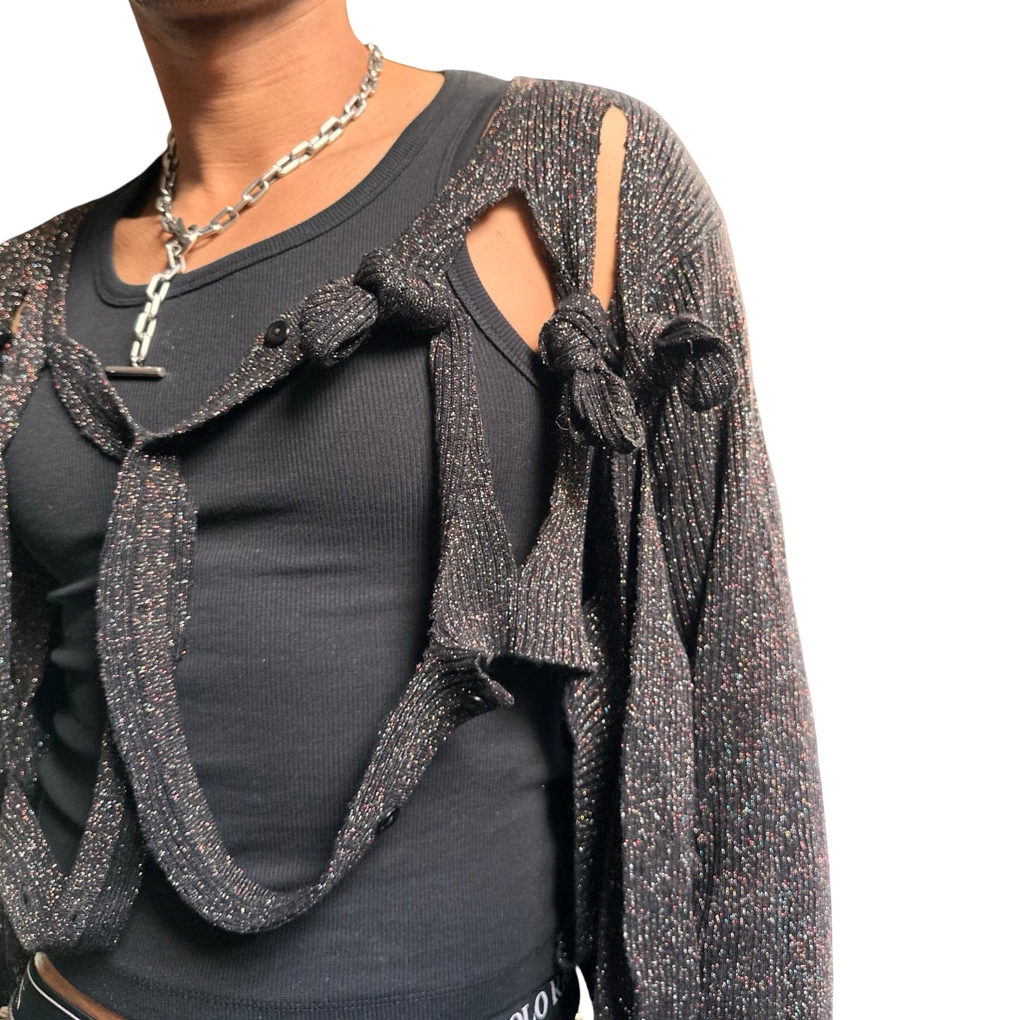 Front left close up of ASTROBOI* black modular rainbow lurex cardigan with cut outs, shimmer finish, and adjustable hanging straps for custom knot styling. Handmade in Brooklyn.
