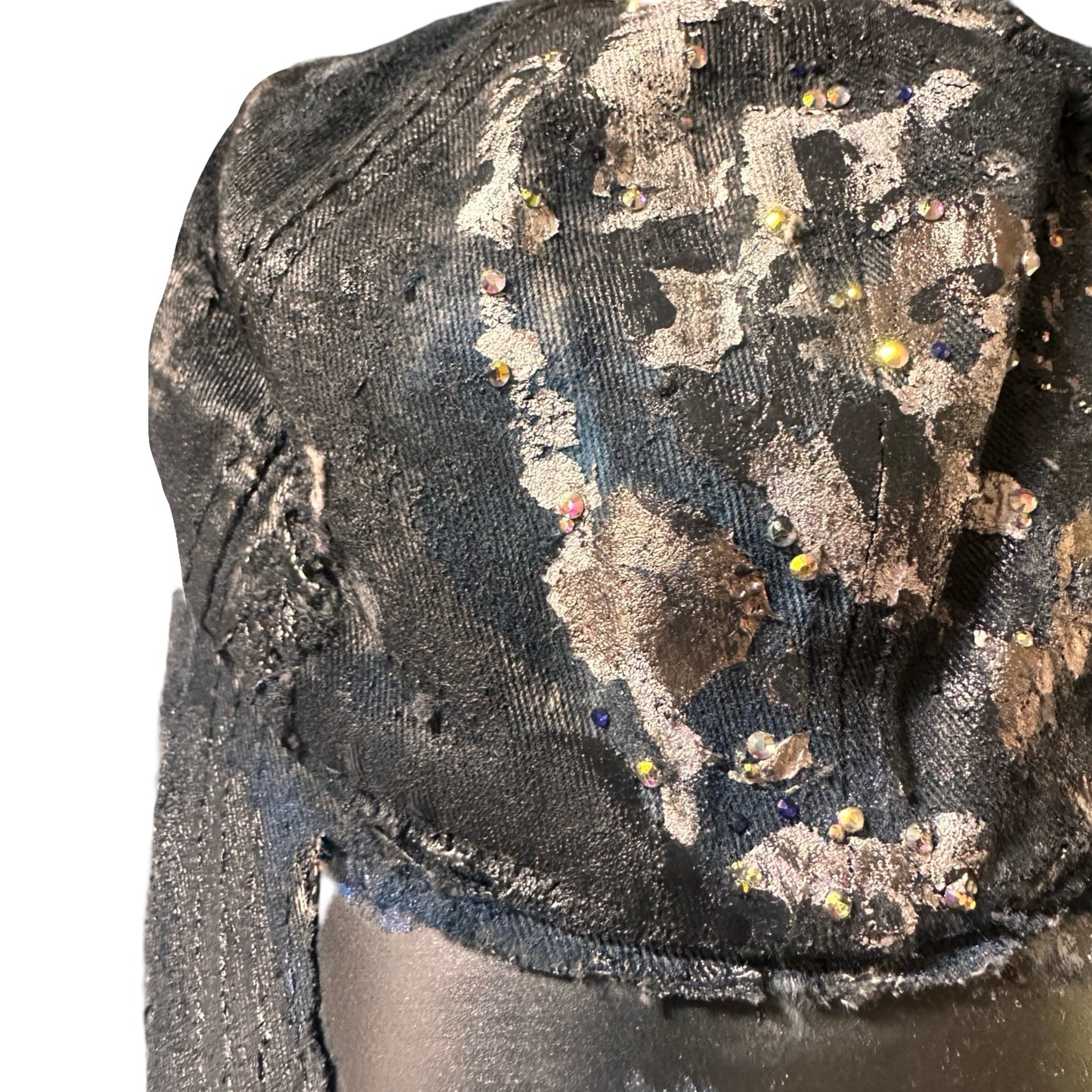 Front close up 2 of Black acid-washed denim hat with silver paint accents, multicolored rhinestones, and a ripped visor seam, customized by ASTROBOI* STUDIO.