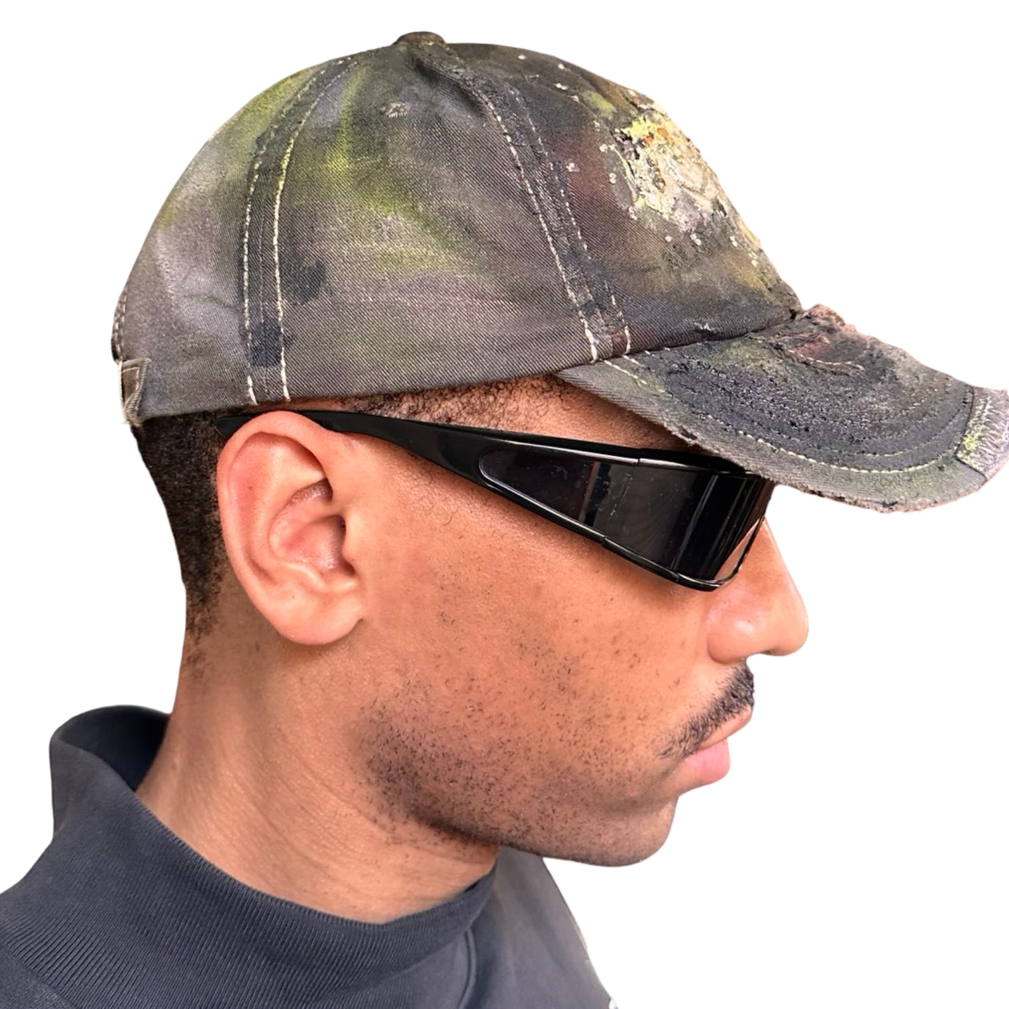 Right of “Green and brown distressed ASTROBOI* Hawaii hat with rhinestones, metallic paint, and sterling-steel piercings, customized in NYC.”