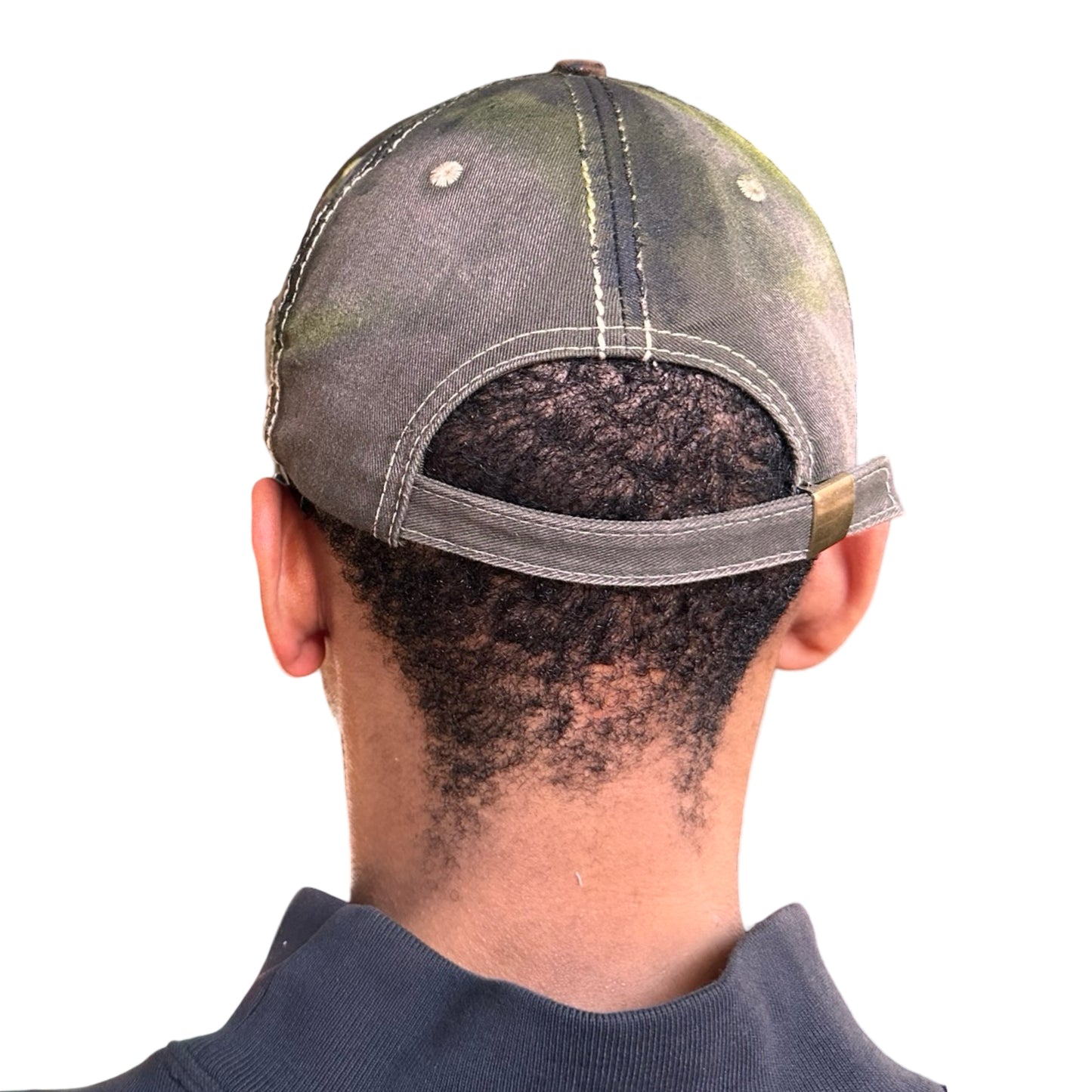 Back of “Green and brown distressed ASTROBOI* Hawaii hat with rhinestones, metallic paint, and sterling-steel piercings, customized in NYC.”