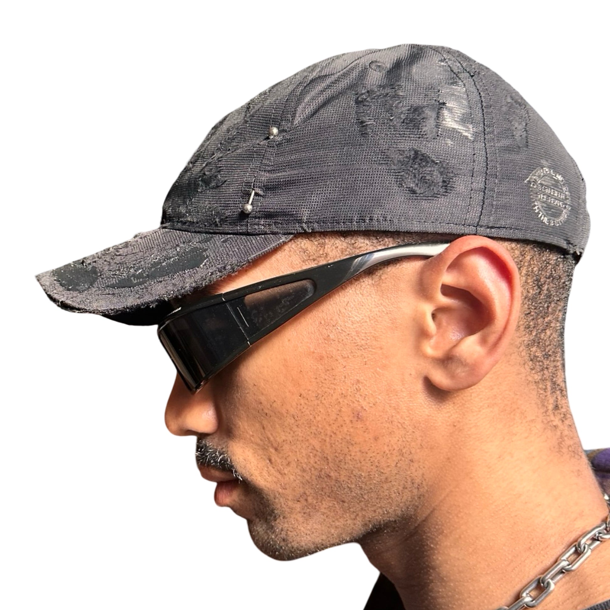 Left side of Black Adidas hat customized by ASTROBOI* with distressing, black painted accents, and stainless steel piercings.
