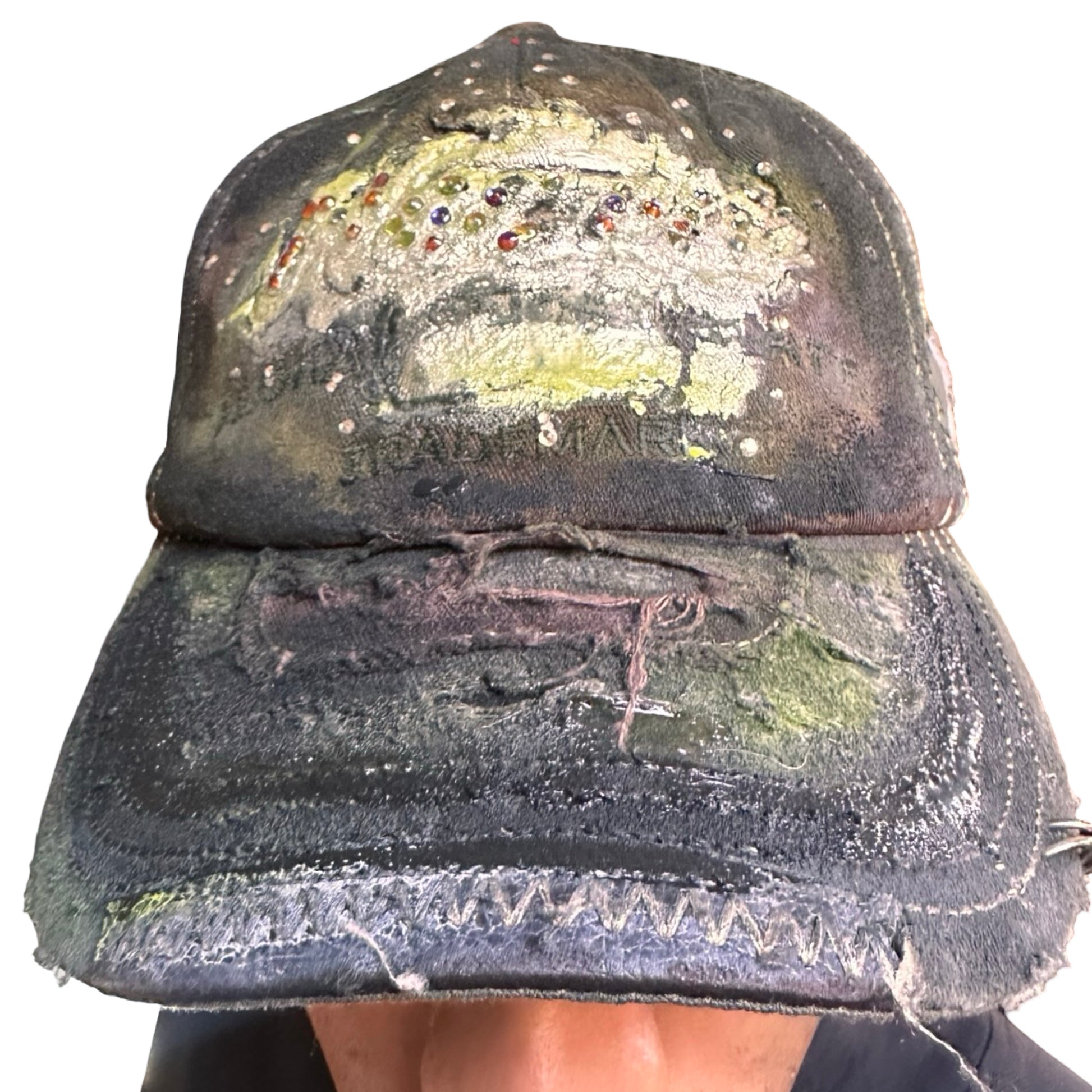Front of “Green and brown distressed ASTROBOI* Hawaii hat with rhinestones, metallic paint, and sterling-steel piercings, customized in NYC.”