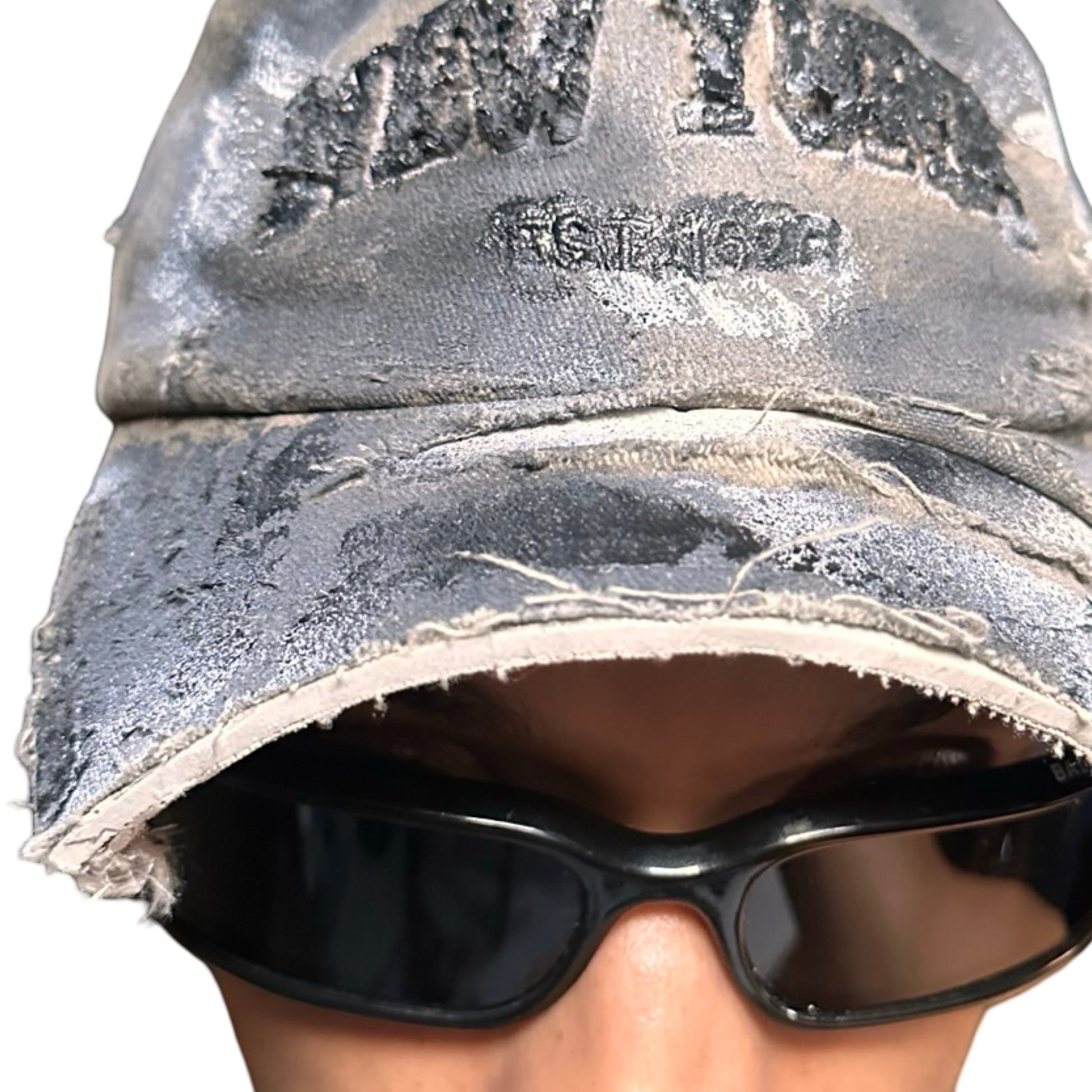 Close up view of ASTROBOI* tan and black New York logo hat with distressed half visor and black and white paint detailing.