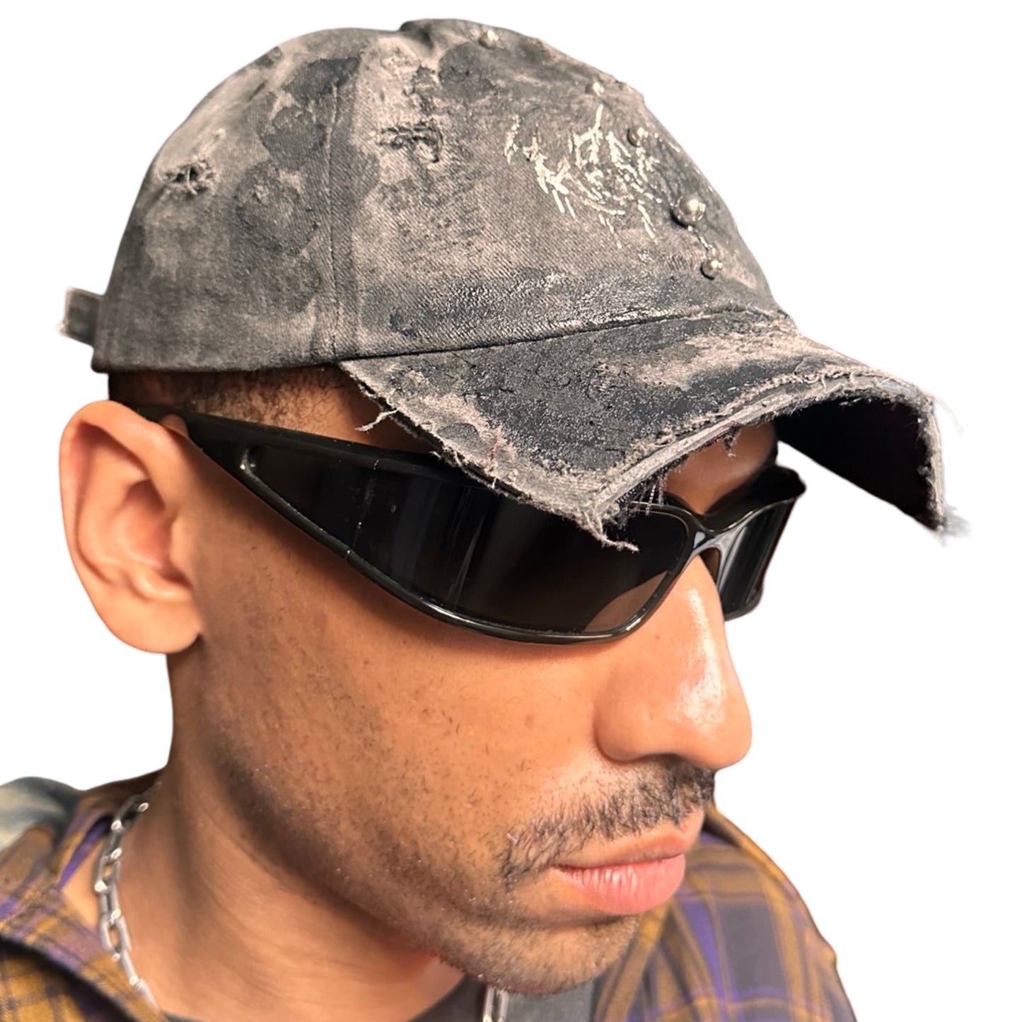 Front right of Black distressed half-visor hat with barbed-wire logo, adjustable strap, black paint details, and stainless steel piercings along the brim.