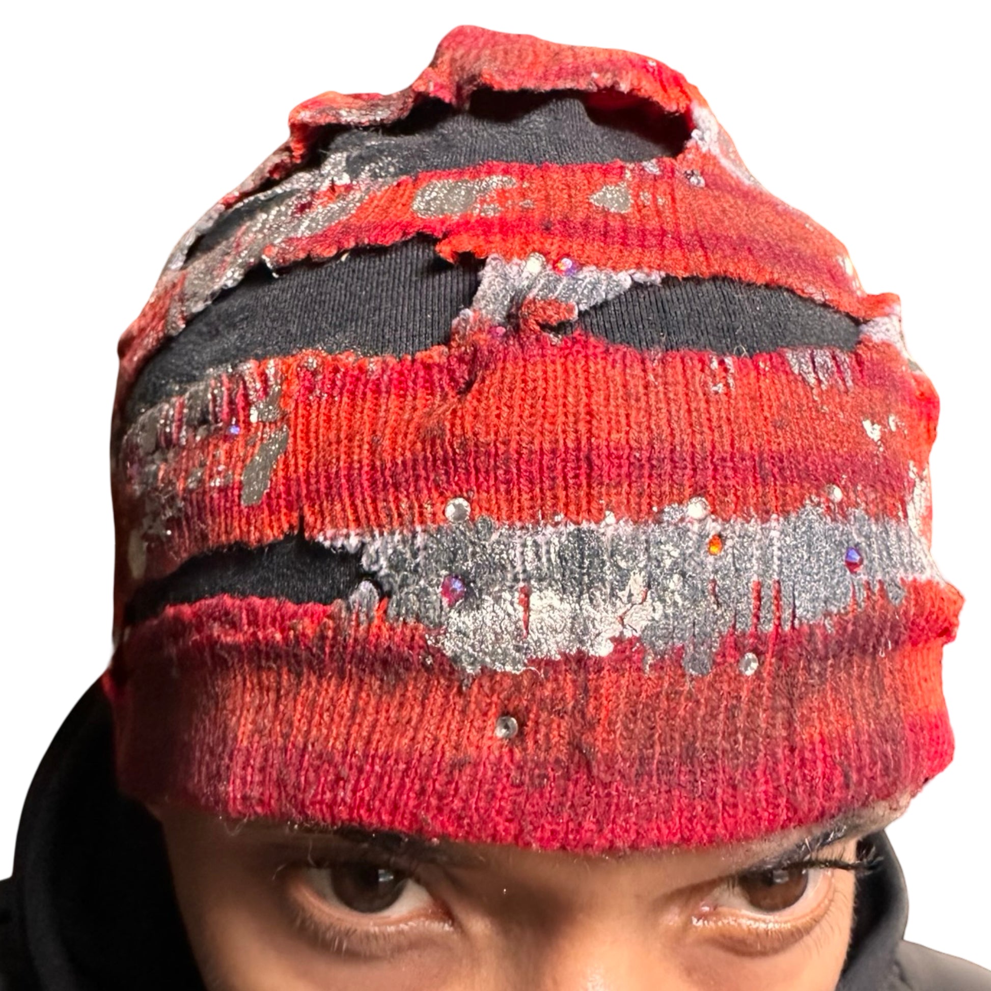 Close up 2 of ASTROBOI* orange and red striped beanie with cutouts, black fleece lining, rhinestones, and metallic paint. Distressed Y2K custom hat handmade in NYC.