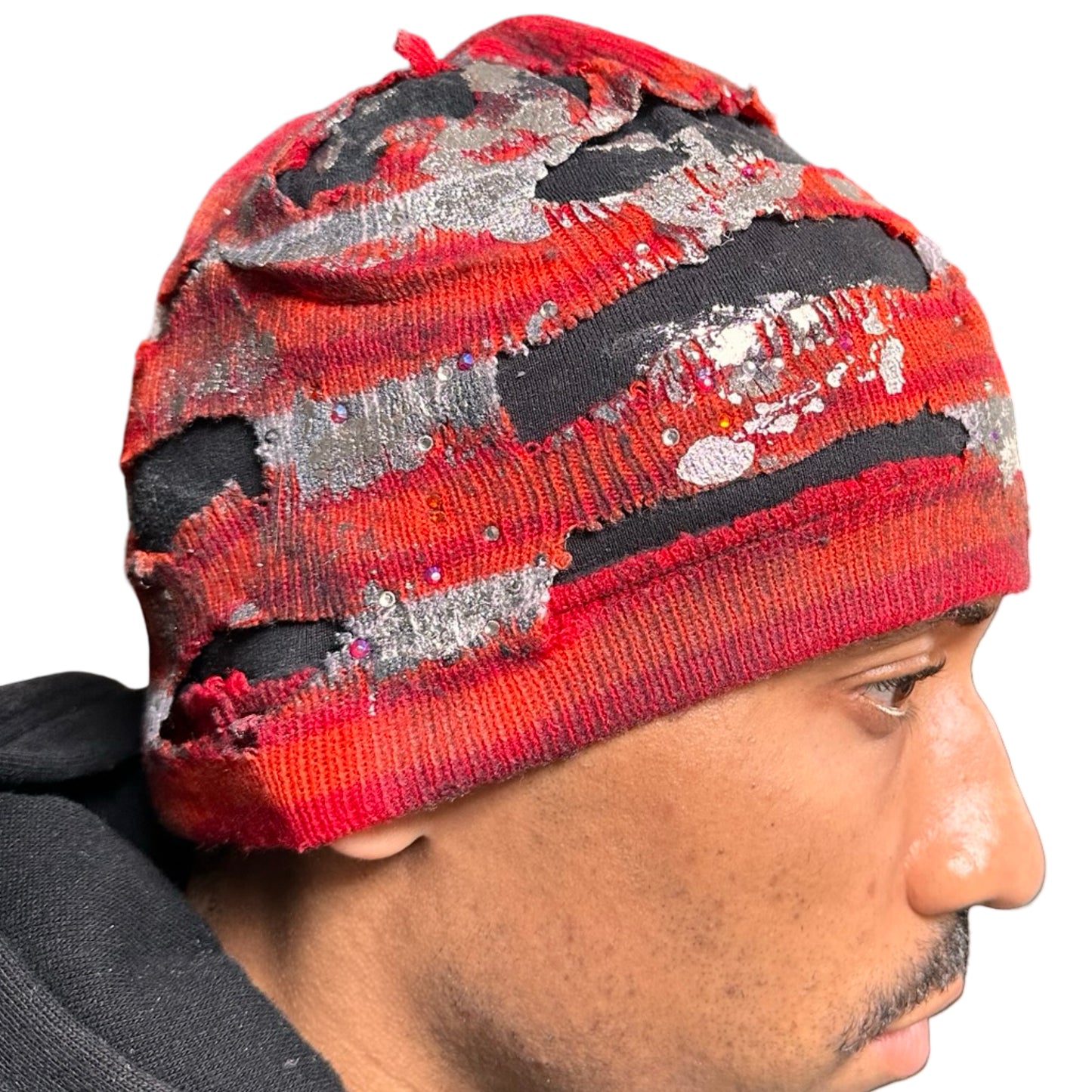 Right of ASTROBOI* orange and red striped beanie with cutouts, black fleece lining, rhinestones, and metallic paint. Distressed Y2K custom hat handmade in NYC.