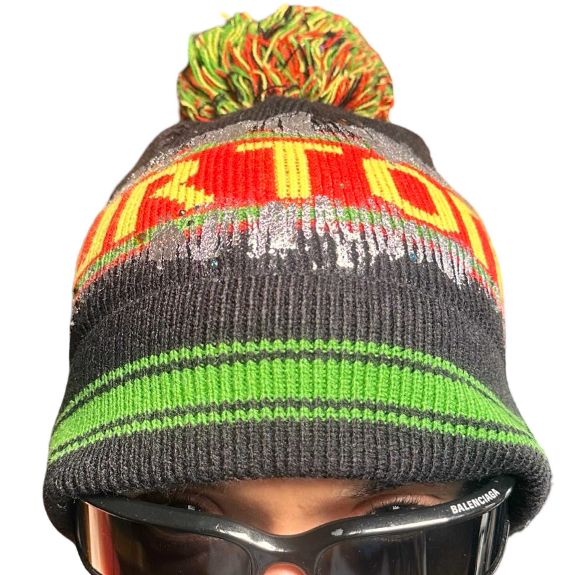 Front of ASTROBOI* x Burton black knit Rastafarian beanie with metallic paint, rhinestones, striped pattern, and pom-pom top. Custom NYC-made winter hat.