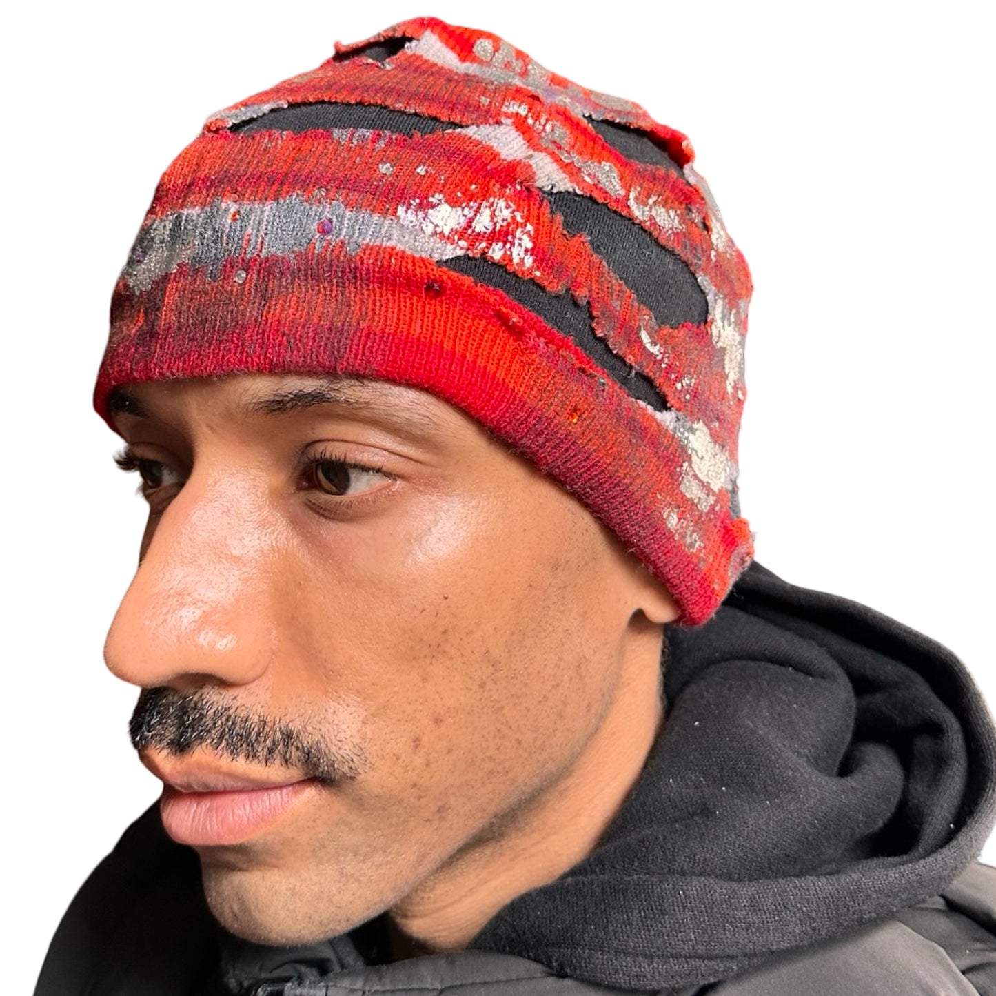 Front left of ASTROBOI* orange and red striped beanie with cutouts, black fleece lining, rhinestones, and metallic paint. Distressed Y2K custom hat handmade in NYC.