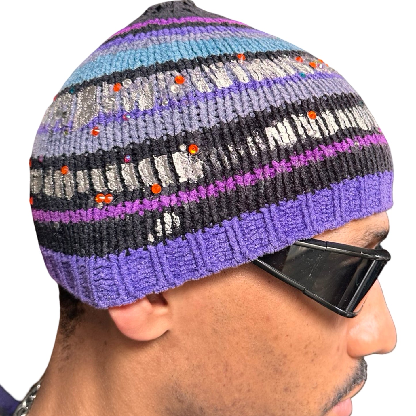 Right side of ASTROBOI* black and purple chenille striped beanie with silver detailing and orange rhinestones, handmade in NYC for a luxe streetwear finish.