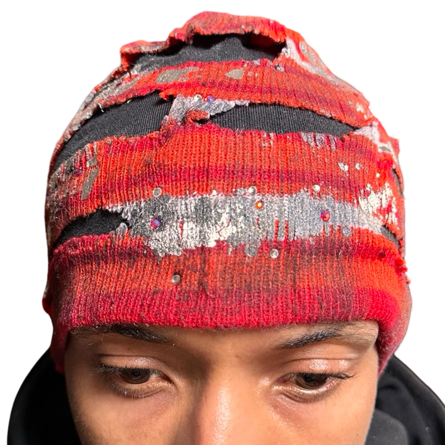 Close up of ASTROBOI* orange and red striped beanie with cutouts, black fleece lining, rhinestones, and metallic paint. Distressed Y2K custom hat handmade in NYC.