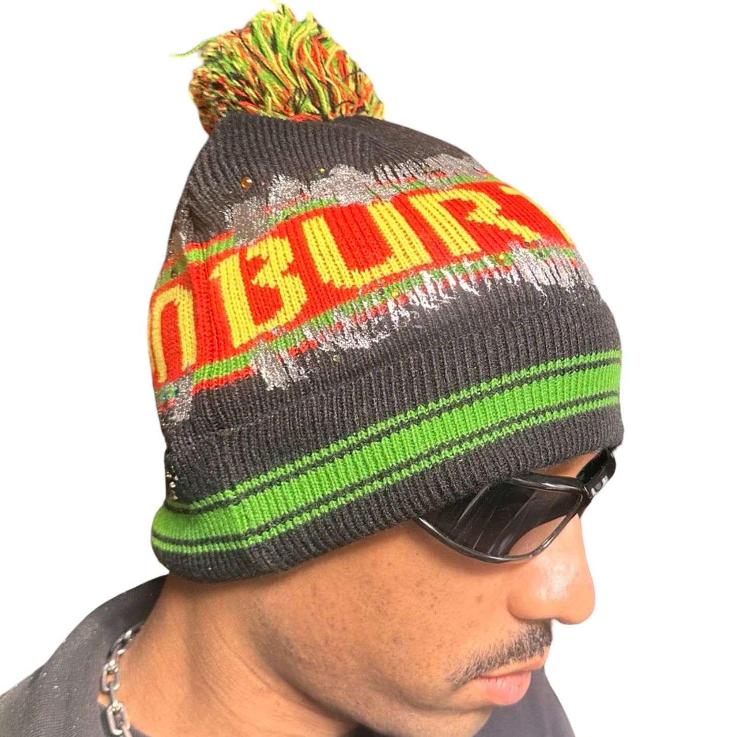 Right side of ASTROBOI* x Burton black knit Rastafarian beanie with metallic paint, rhinestones, striped pattern, and pom-pom top. Custom NYC-made winter hat.
