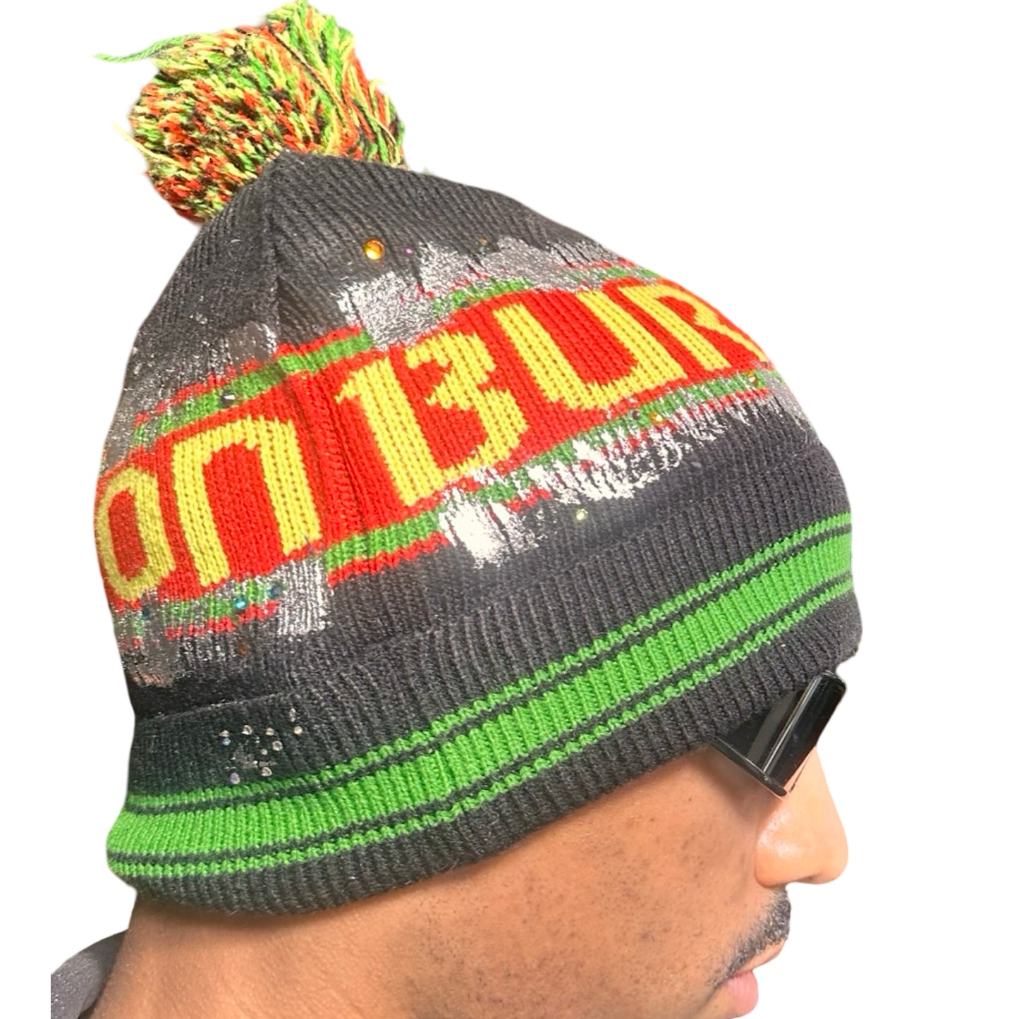 Right side of ASTROBOI* x Burton black knit Rastafarian beanie with metallic paint, rhinestones, striped pattern, and pom-pom top. Custom NYC-made winter hat.