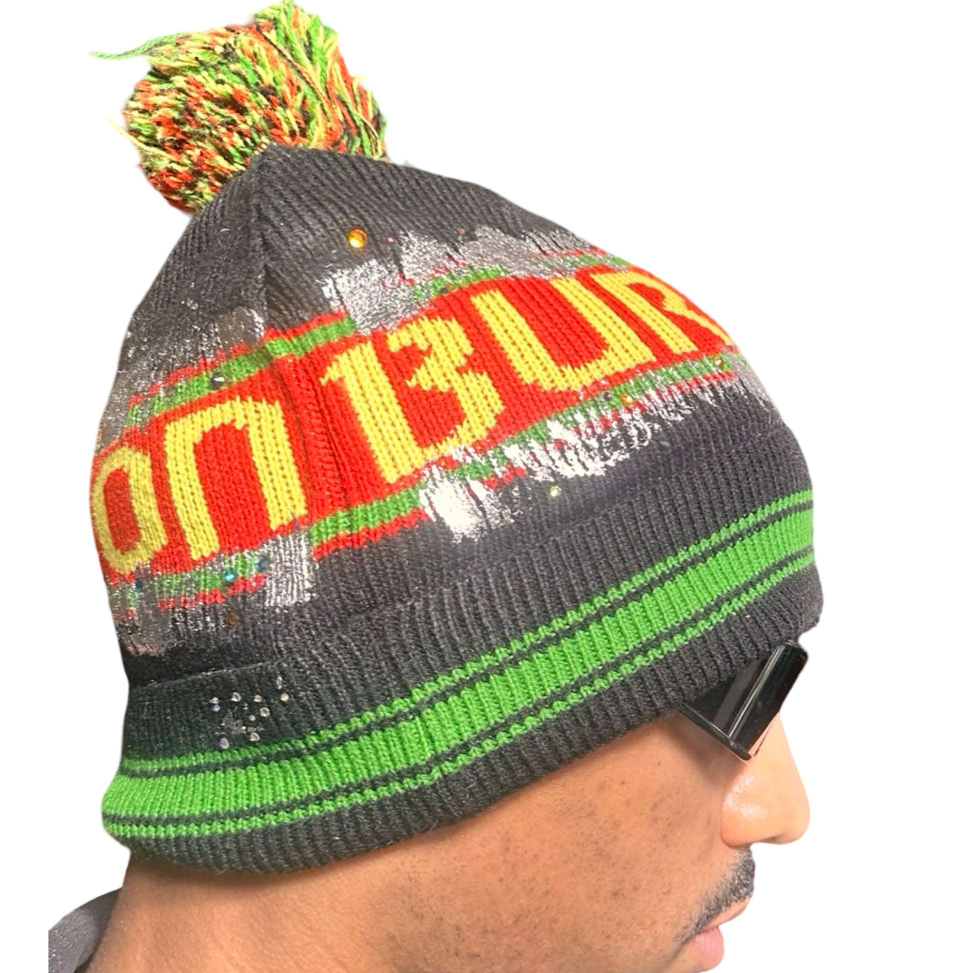 Right side of ASTROBOI* x Burton black knit Rastafarian beanie with metallic paint, rhinestones, striped pattern, and pom-pom top. Custom NYC-made winter hat.