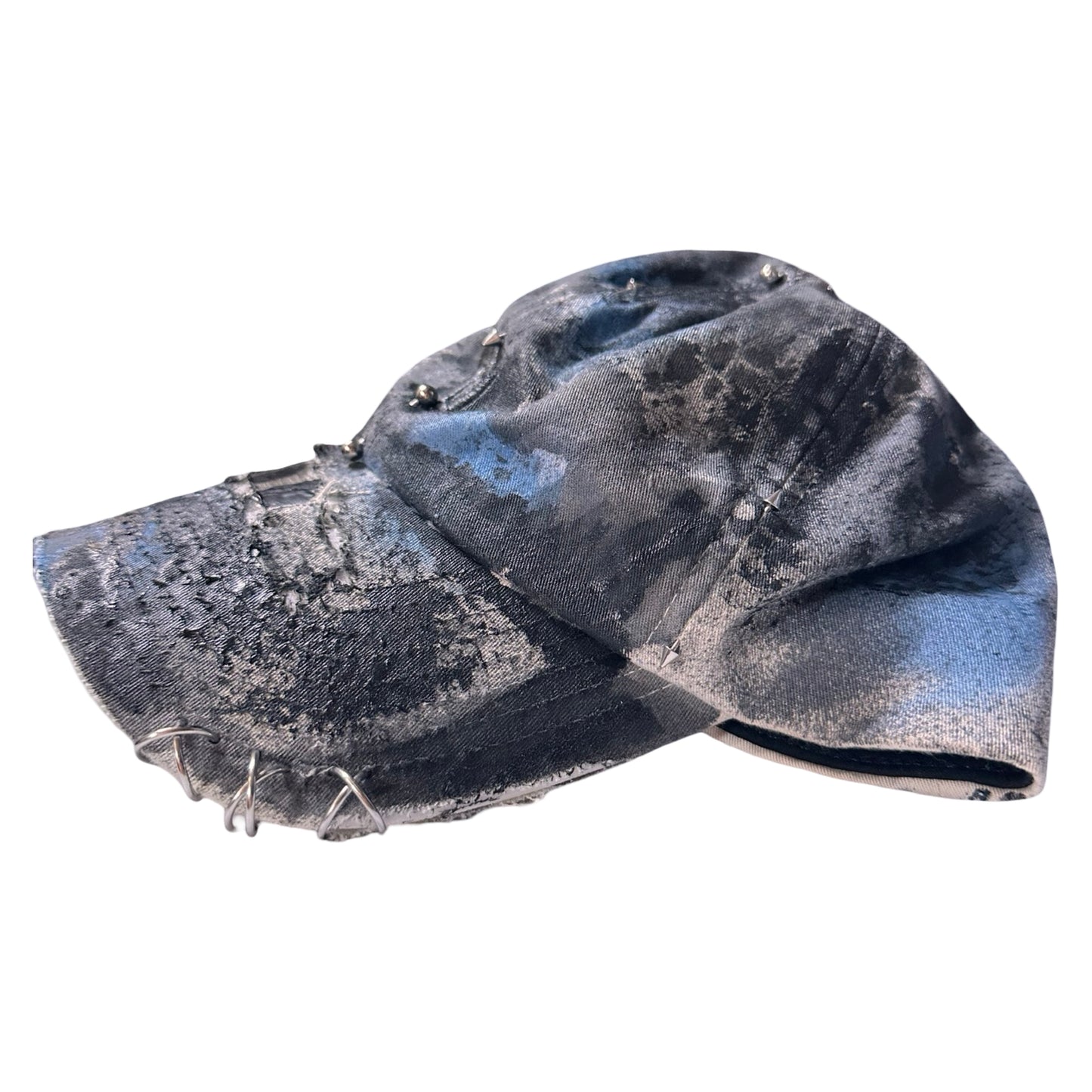 Flat left side of Black Vuori baseball hat customized by ASTROBOI* with blue and black painted details, stainless steel piercings, and an embroidered V logo.